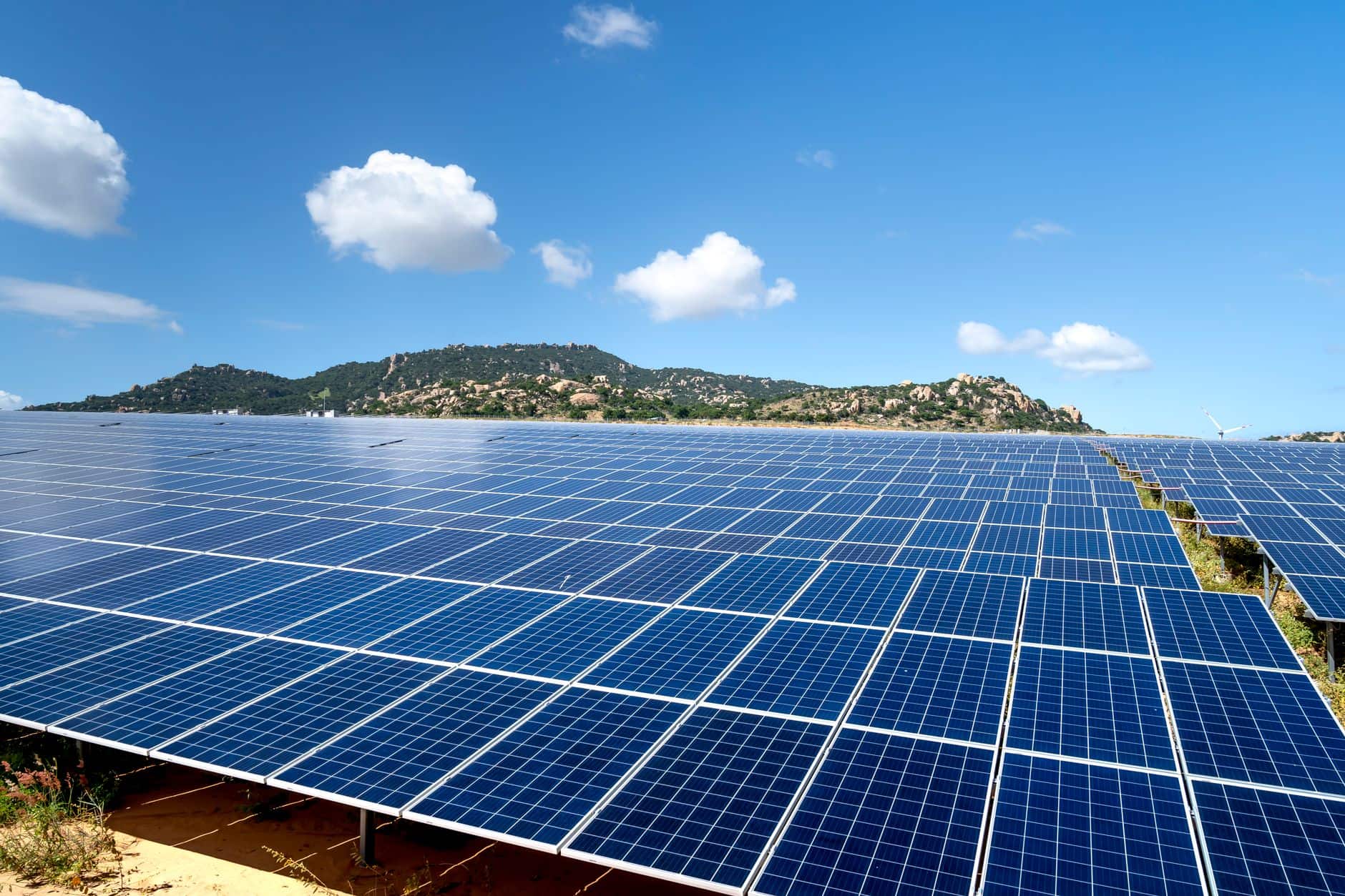 Sprawling solar farm with blue panels under a bright, vibrant sky
