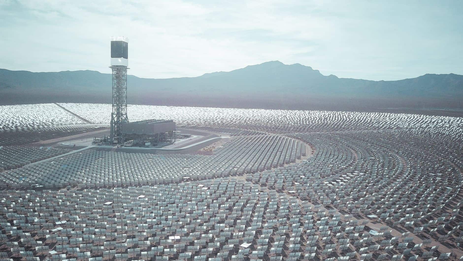 Aerial view of a large solar power station with mountains in the background