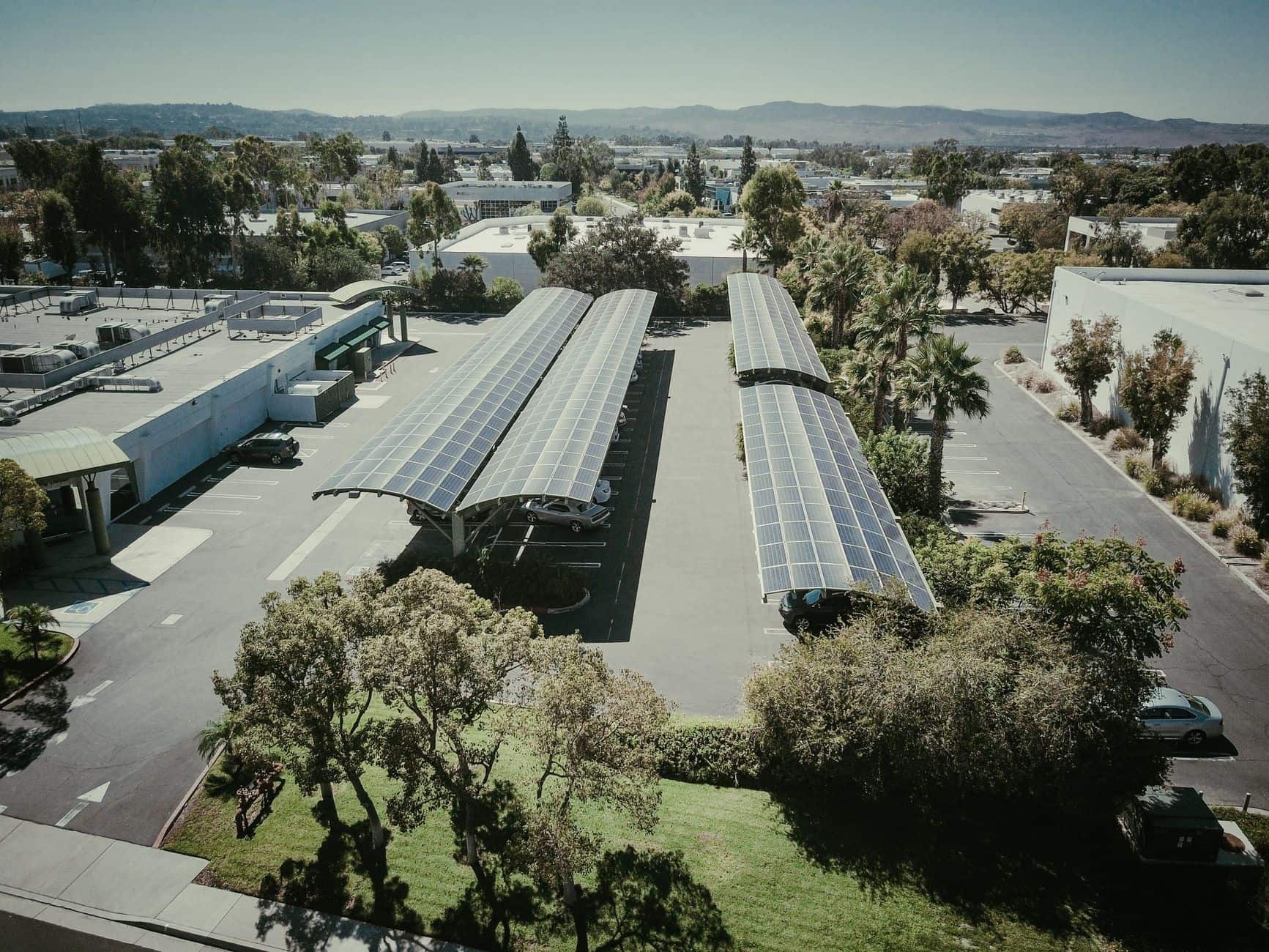 Aerial view of a suburban neighborhood with rooftops covered in solar panels under a clear sky