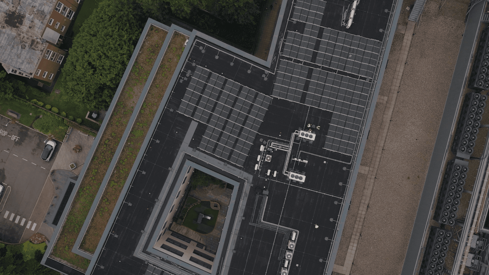 High-angle view of an urban rooftop with solar panels and greenery