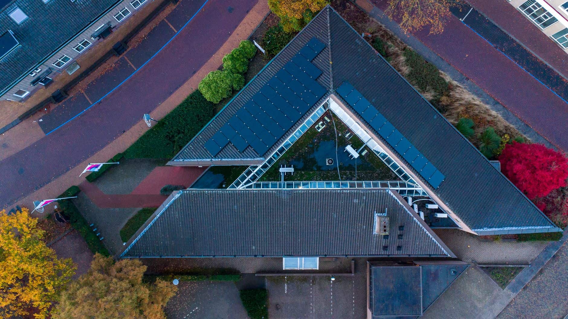 Aerial view of a modern building with solar panels on a triangular roof