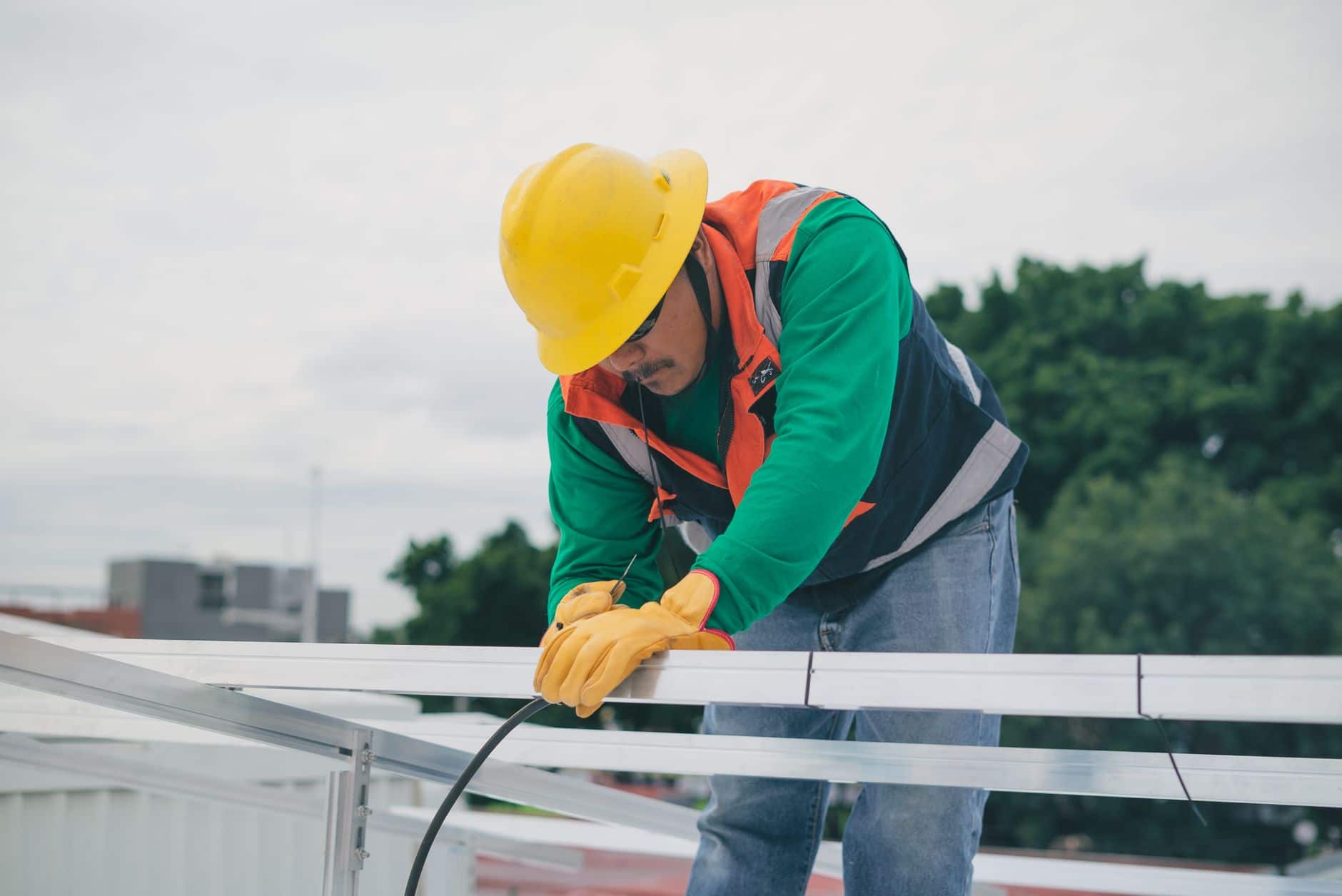 Construction worker in safety gear installing solar panels on a sunny day