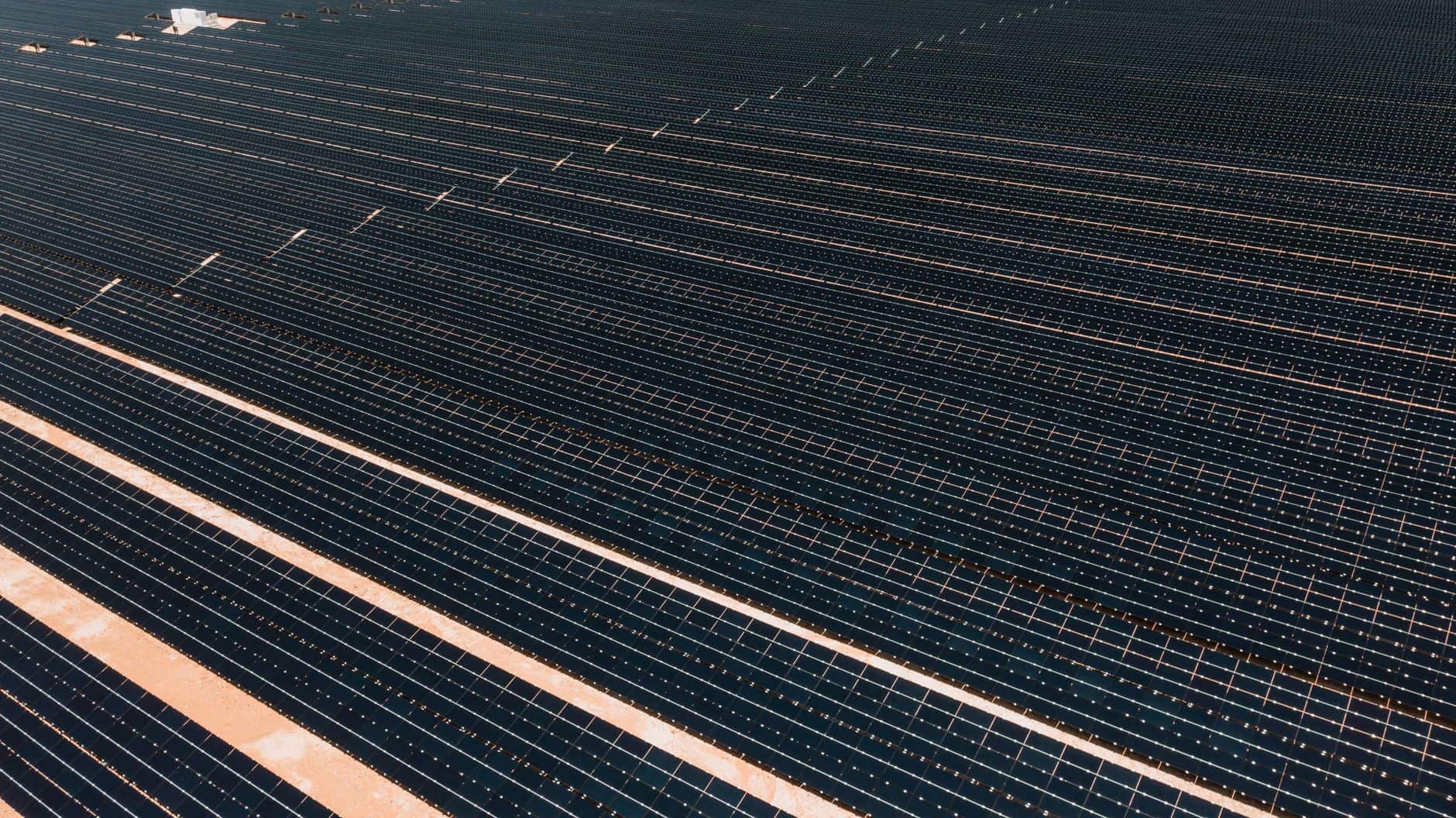 Aerial view of a large solar farm with rows of panels stretching across the landscape
