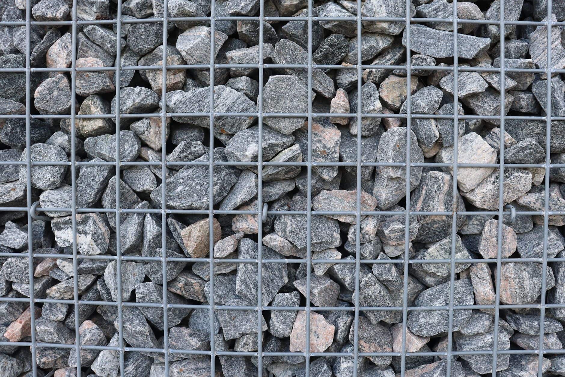 Gabion retaining wall composed of tightly packed natural stones within wire mesh