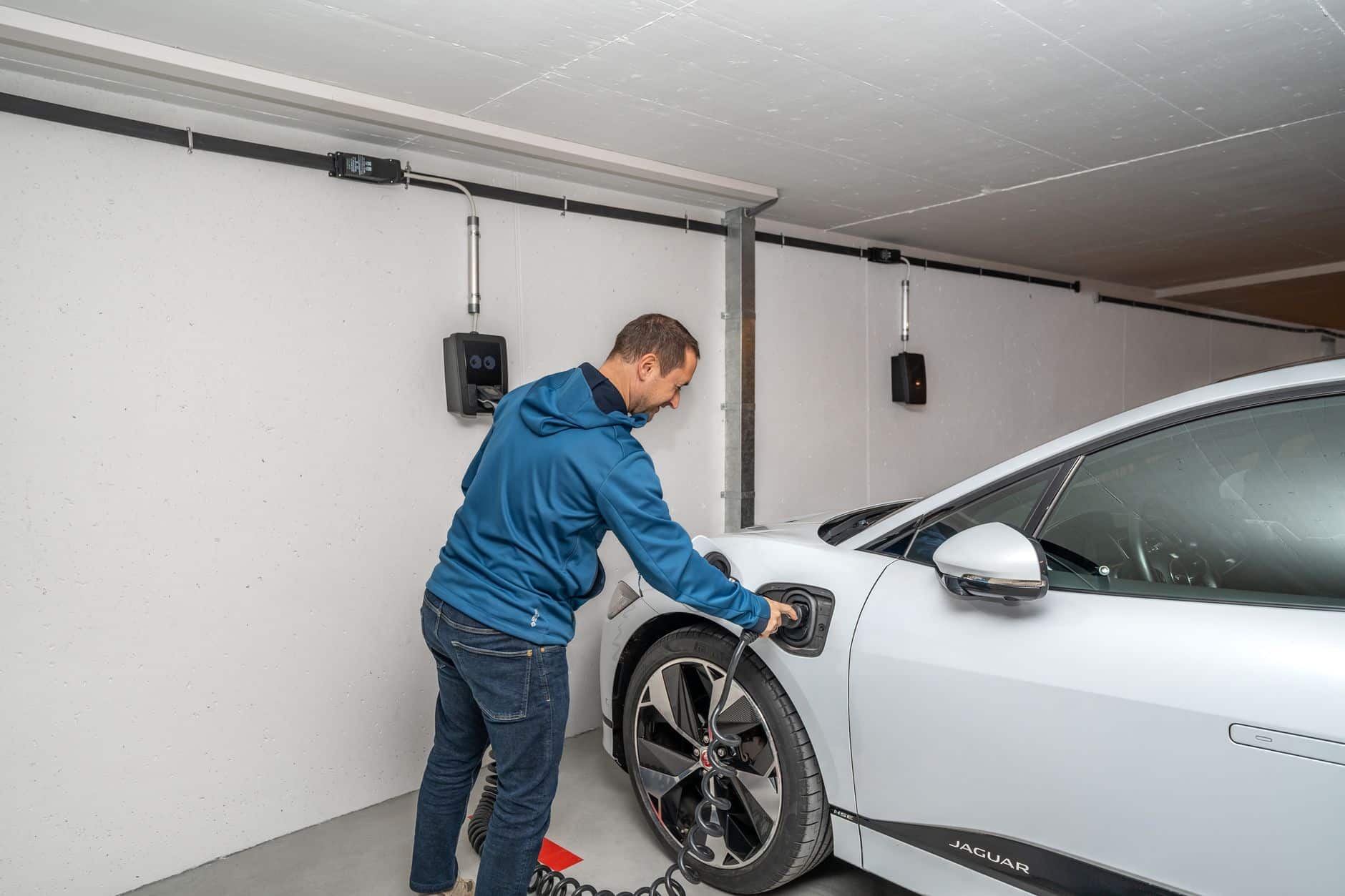 Man connecting an electric car to a charging station in a modern indoor garage