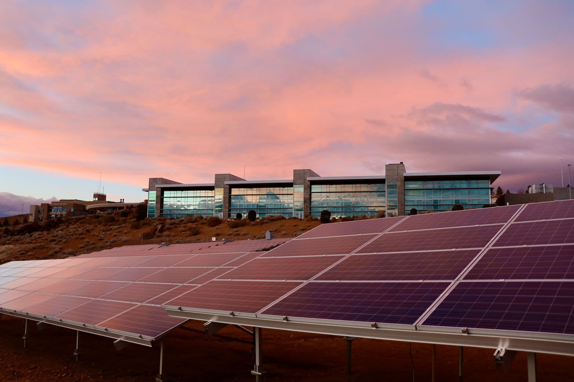 Solar panels mounted on a modern building with a sunset background