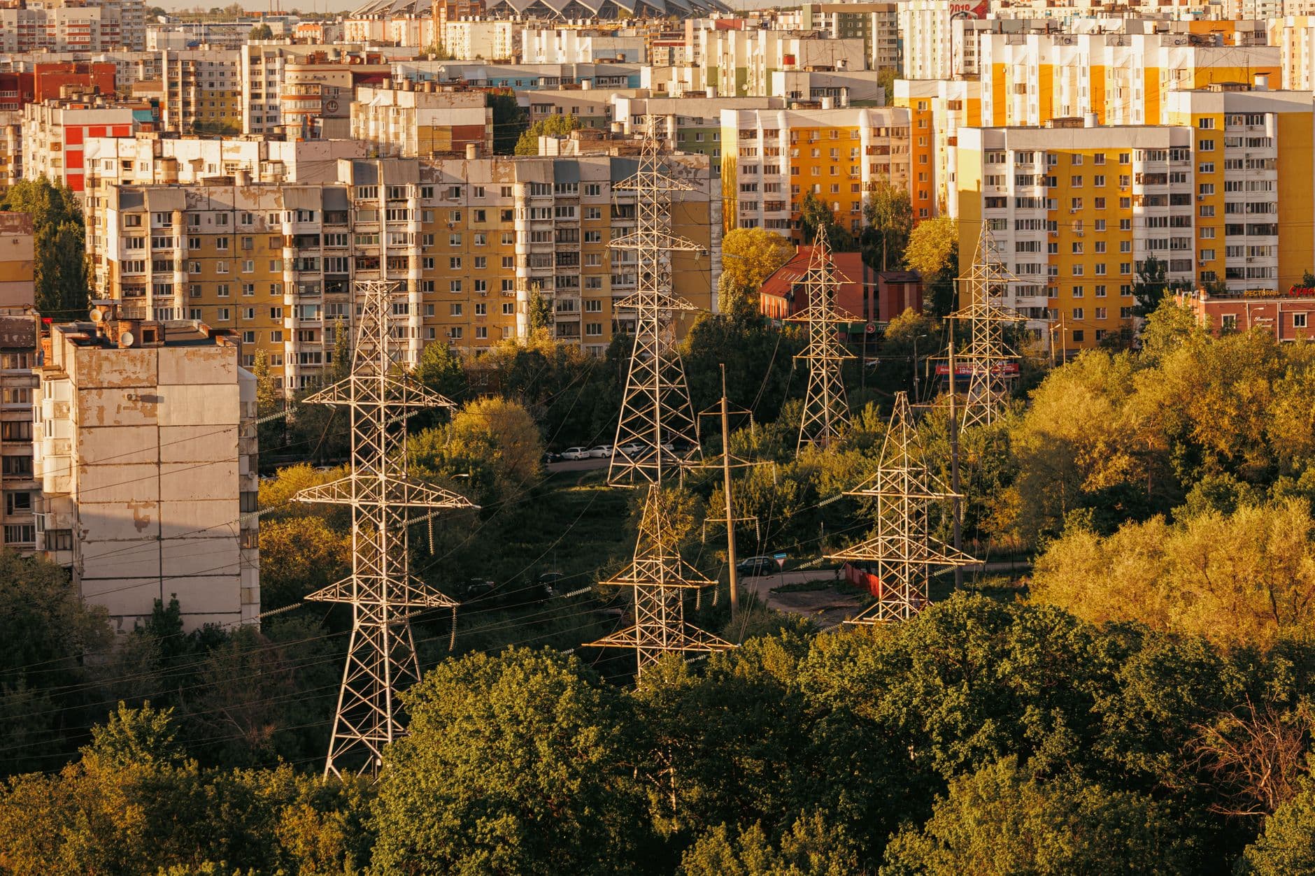 Aerial view of a city with high‑voltage power lines and apartment buildings, illustrating the grid that can be protected by solar backup