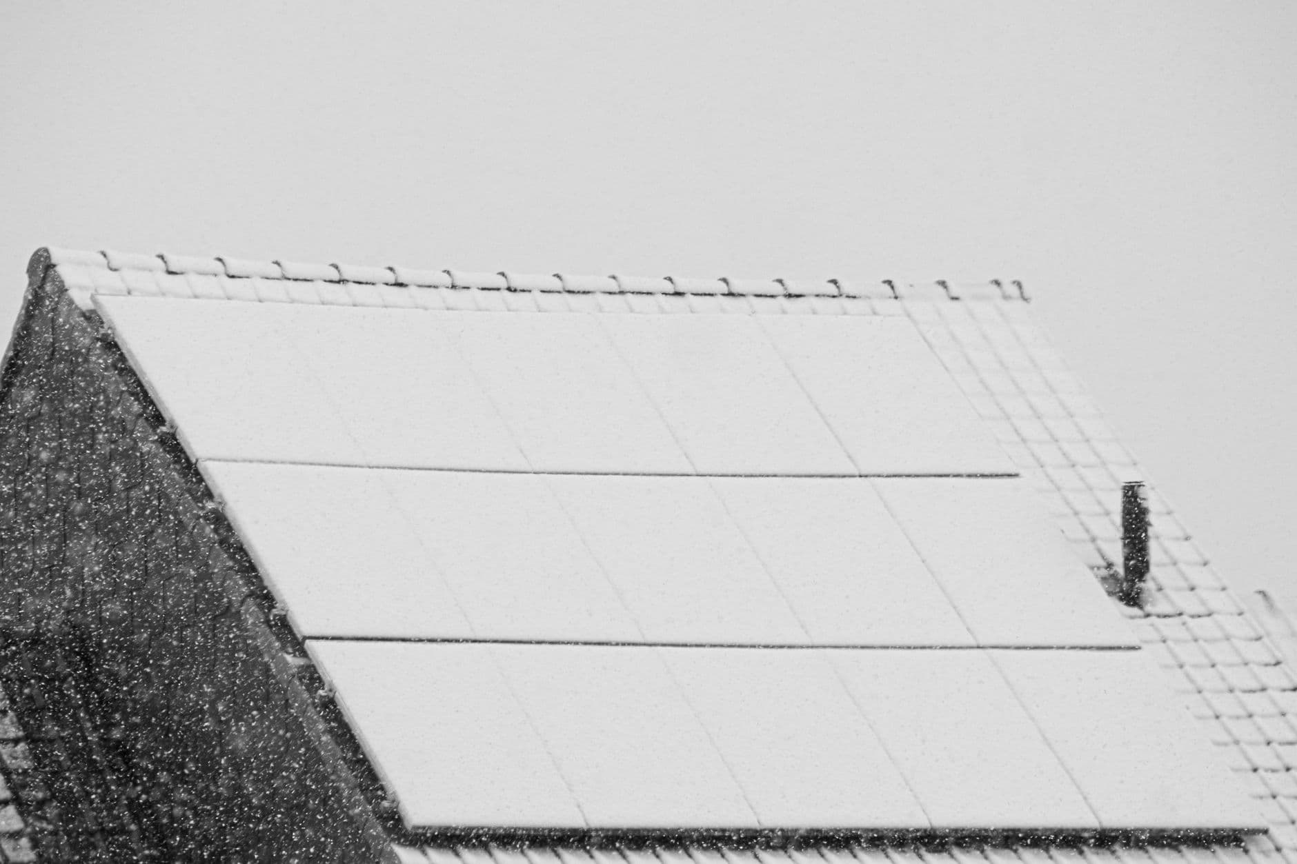 Snow-covered solar panels on a rooftop in winter