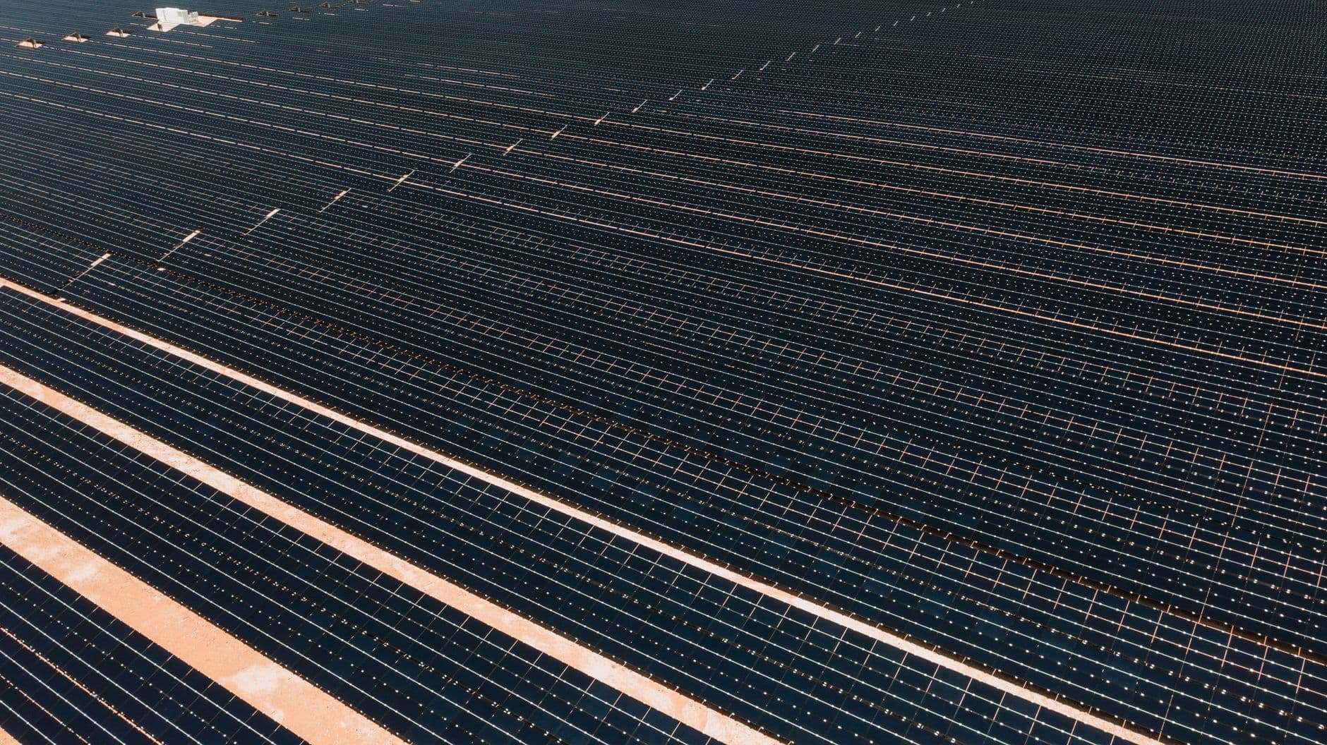 Aerial view of a large solar farm with rows of panels stretching across the landscape