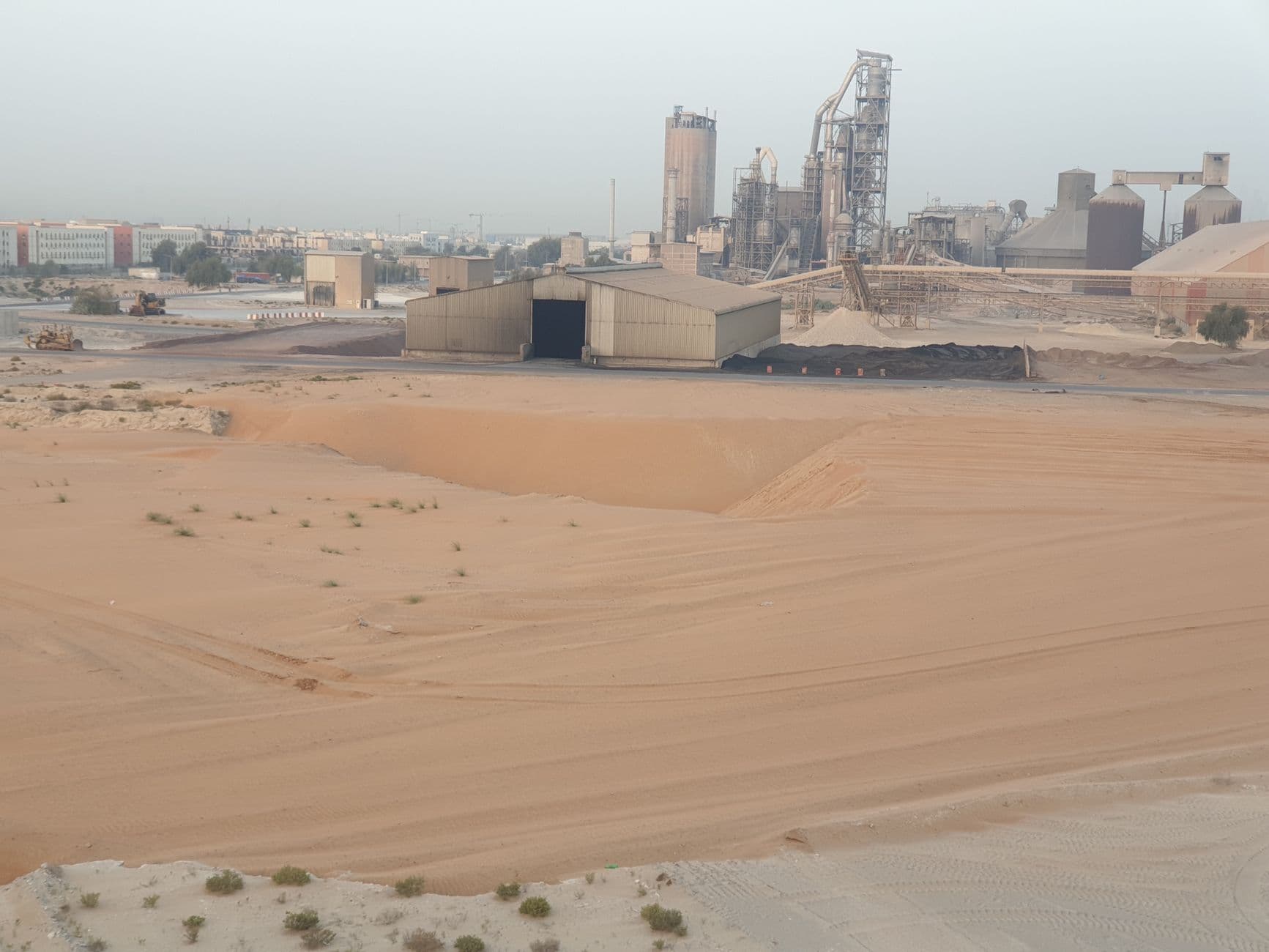 Large industrial plant in a desert with sand dunes