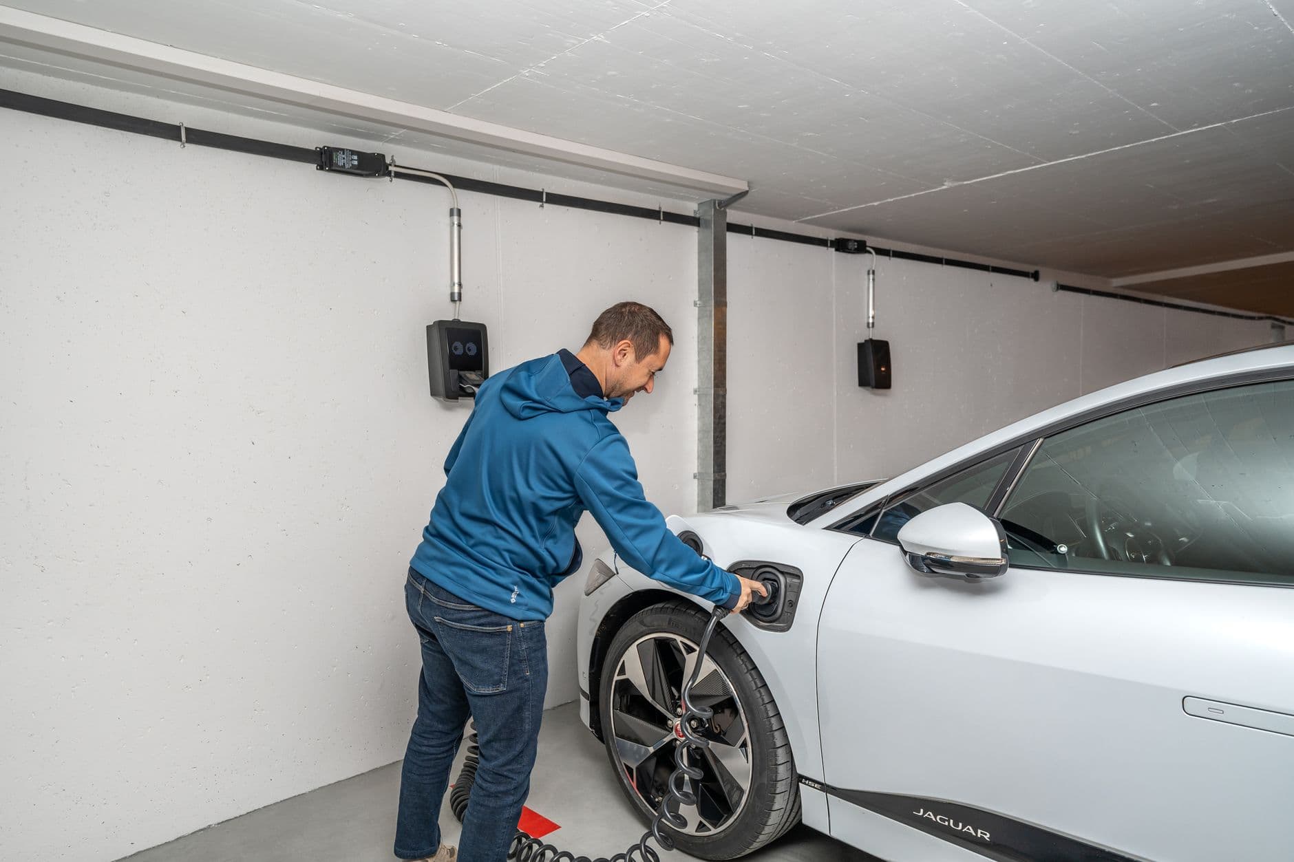 Man connecting an electric car to a charging station in a modern indoor garage