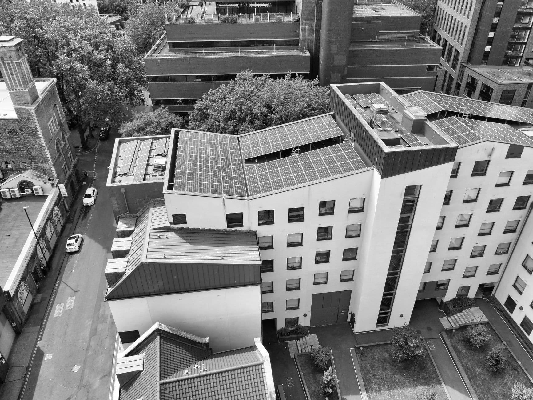 Aerial black-and-white view of city buildings with rooftop solar panels