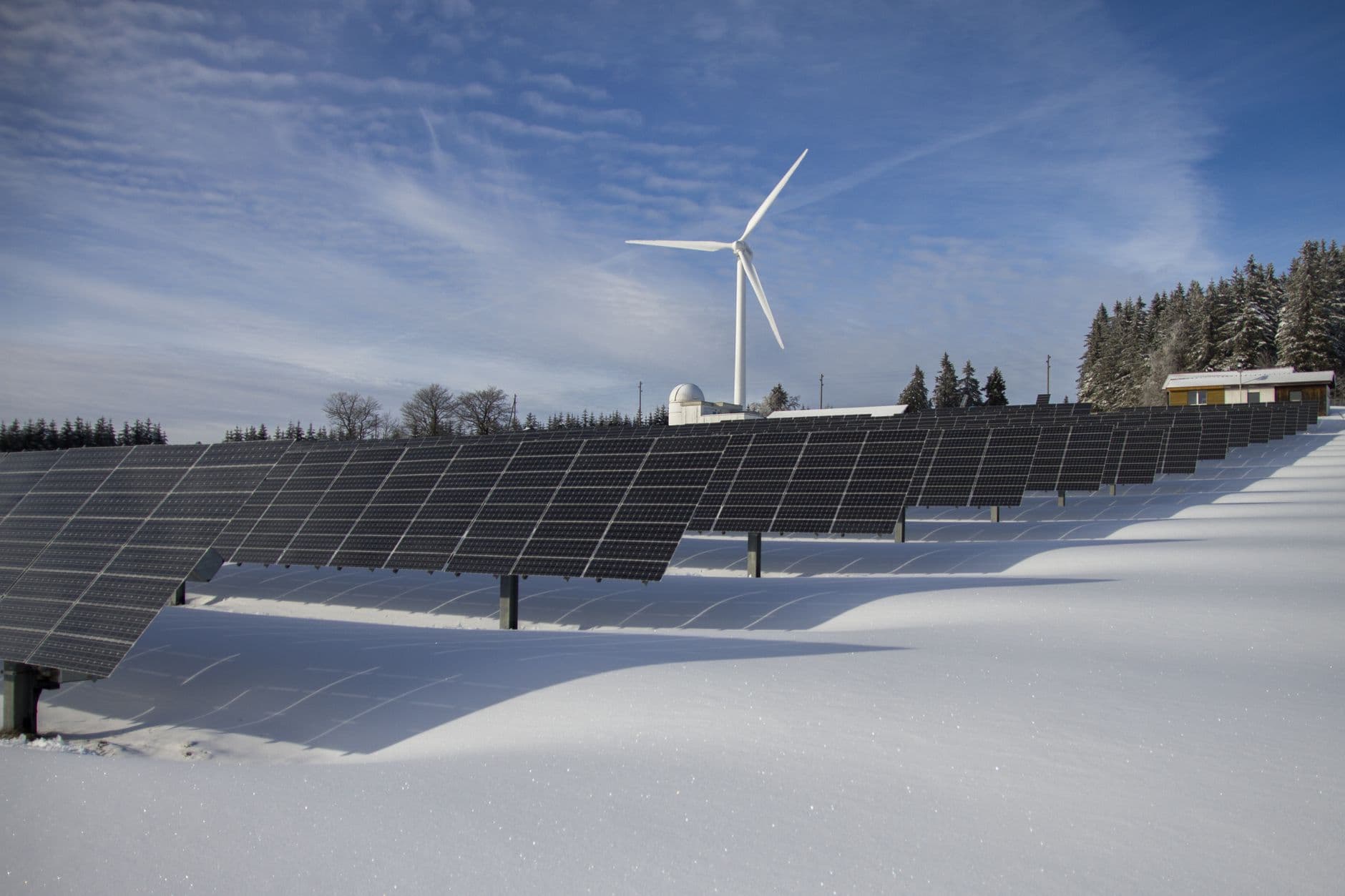 Solar panels and wind turbine in a snowy Arctic landscape