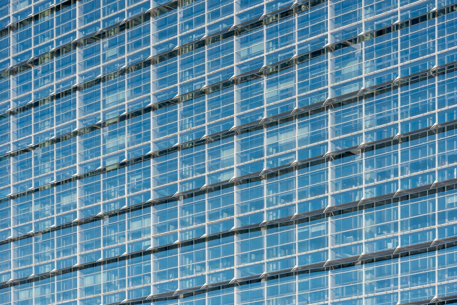 Elegant glass facade of a high-rise building reflecting the sky