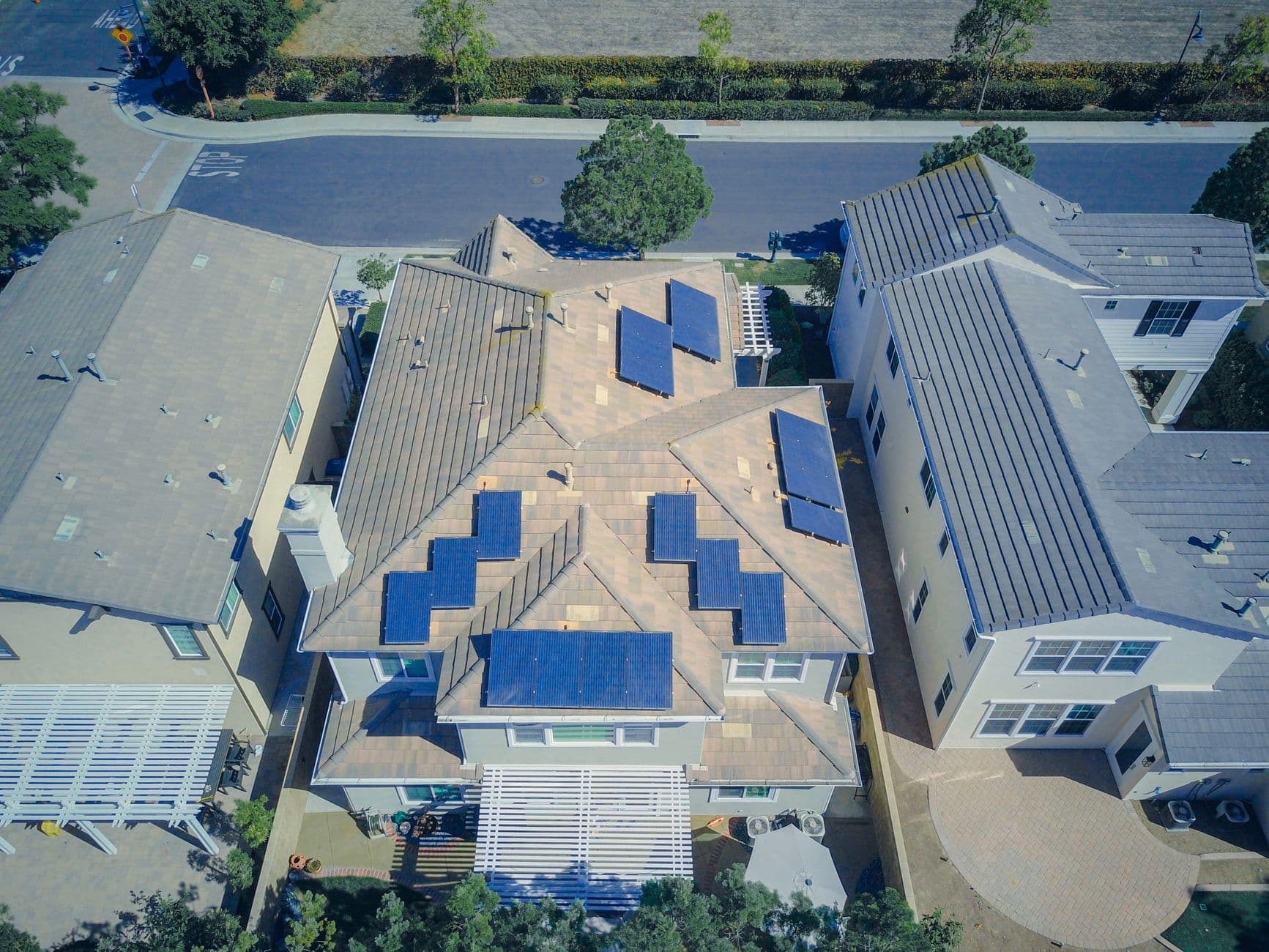 Aerial view of suburban homes with rooftop solar panels under a sunny sky