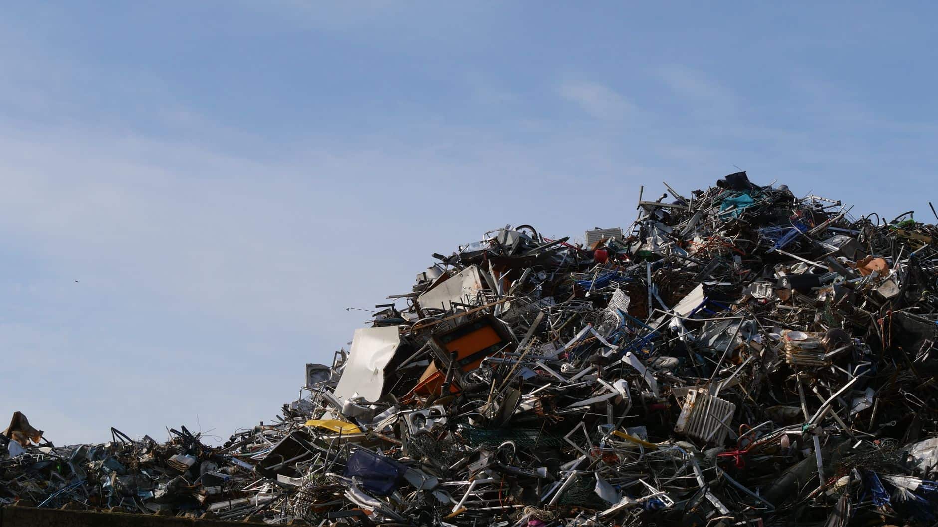 Large pile of metal scrap and debris in a junkyard under a clear sky