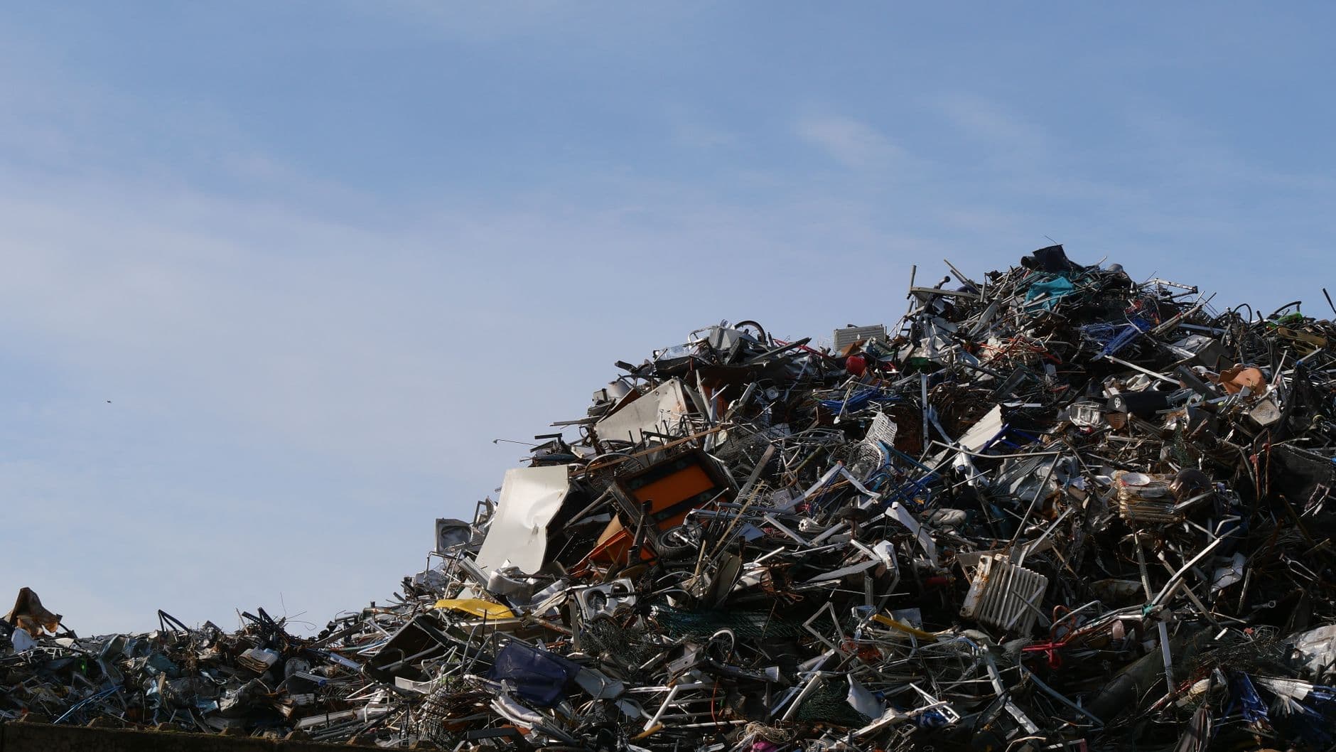Large pile of metal scrap and debris in a junkyard under a clear sky