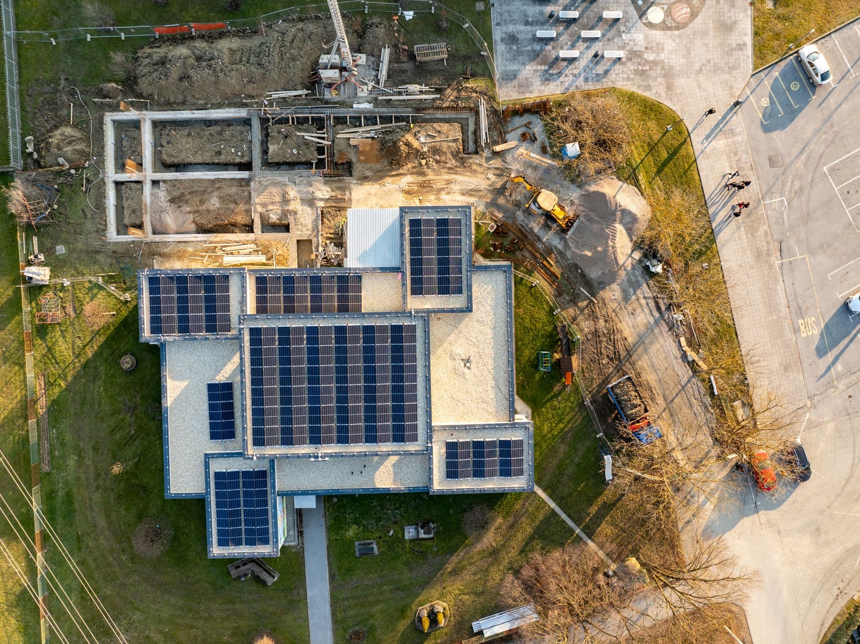 Aerial top-down view of a building under construction with solar panels installed on the roof