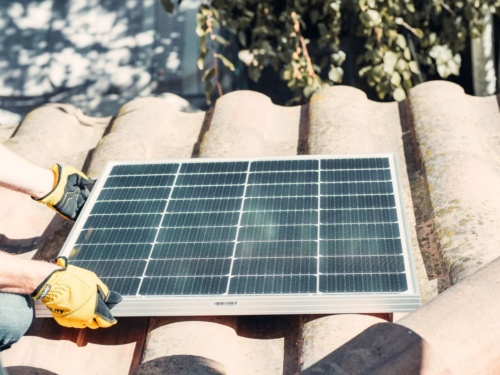 Technician fitting solar panel on a rooftop in sunlight