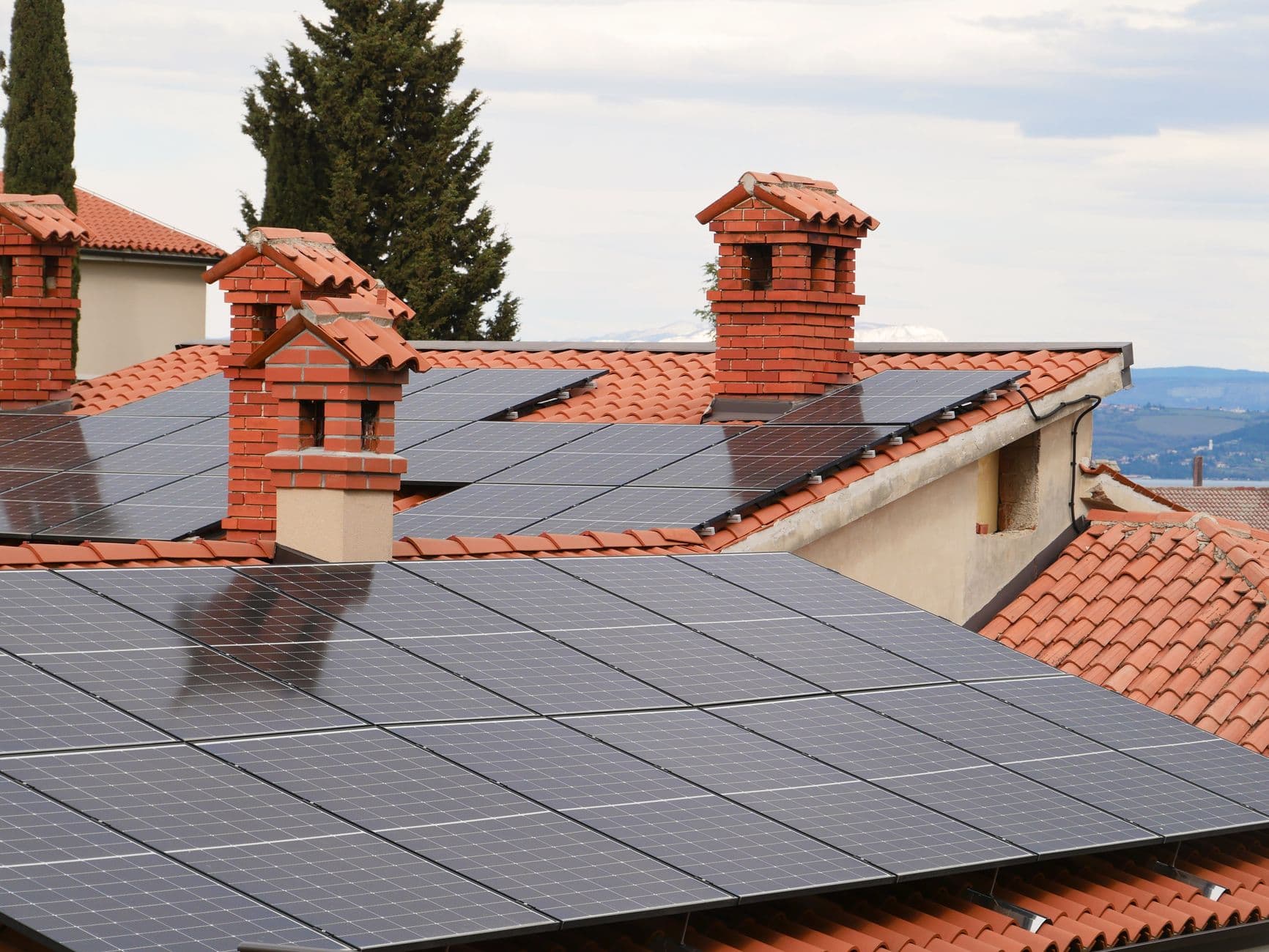 Solar panels installed on tiled residential roofs with chimneys, showing clean energy generation