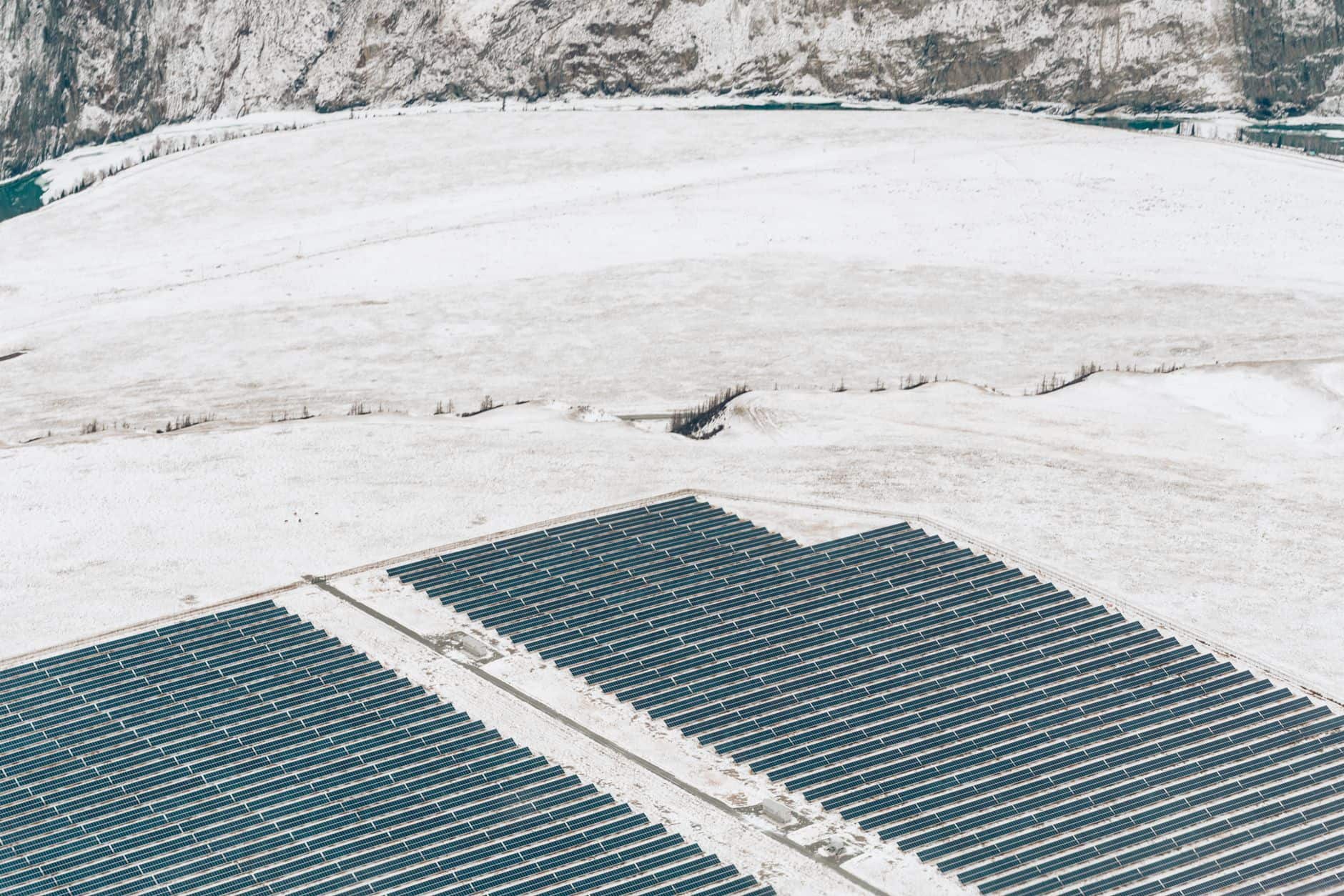 Aerial view of solar panels covering a snowy field, illustrating renewable energy installations