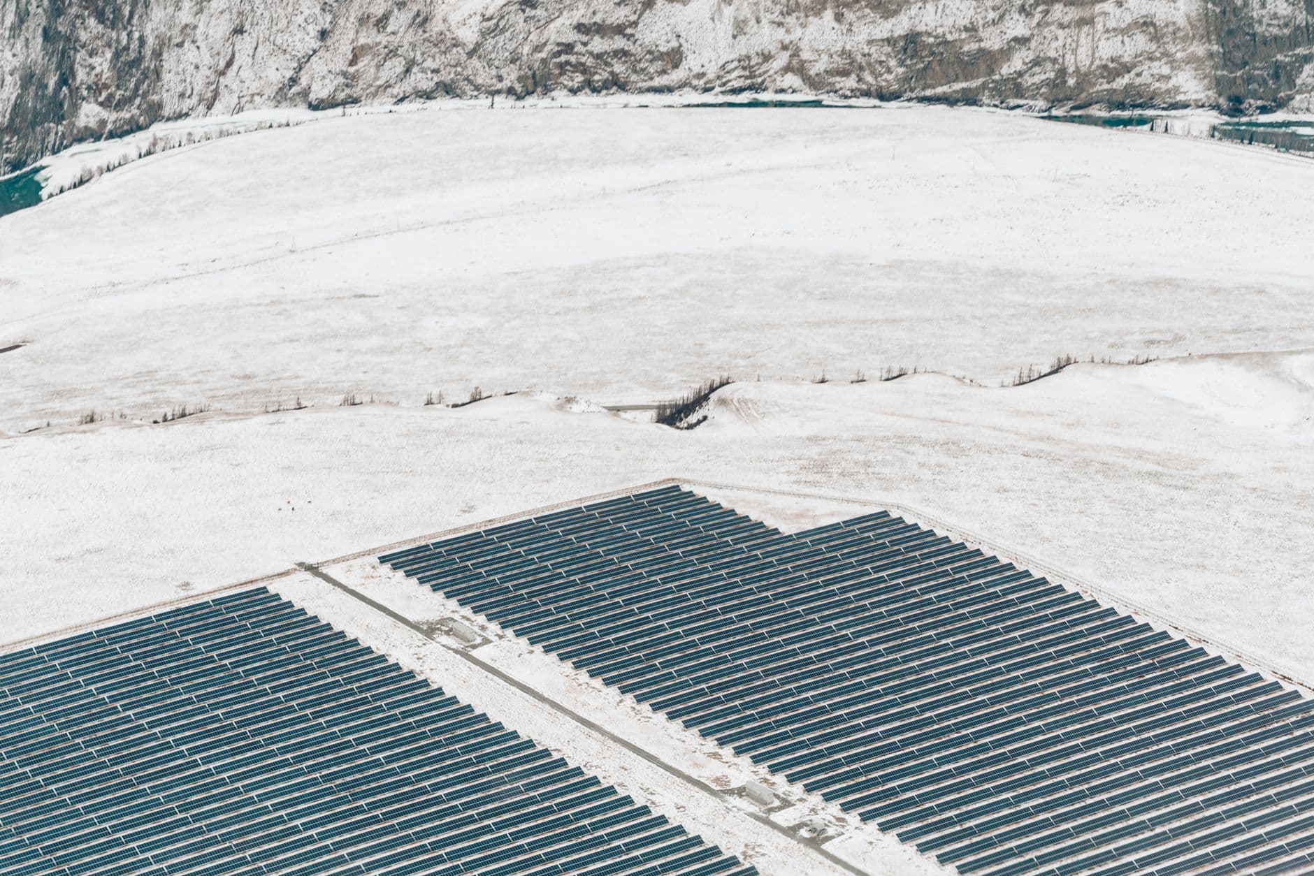 Aerial view of solar panels covering a snowy field, illustrating renewable energy installations