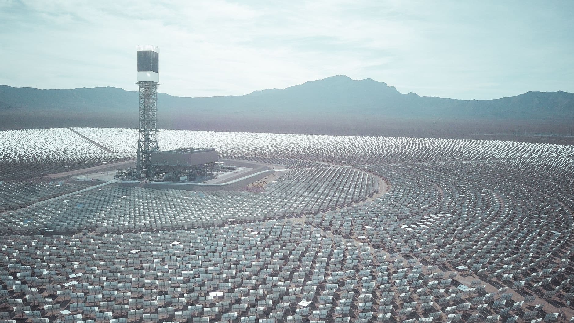 Aerial view of a large solar power station with mountains in the background