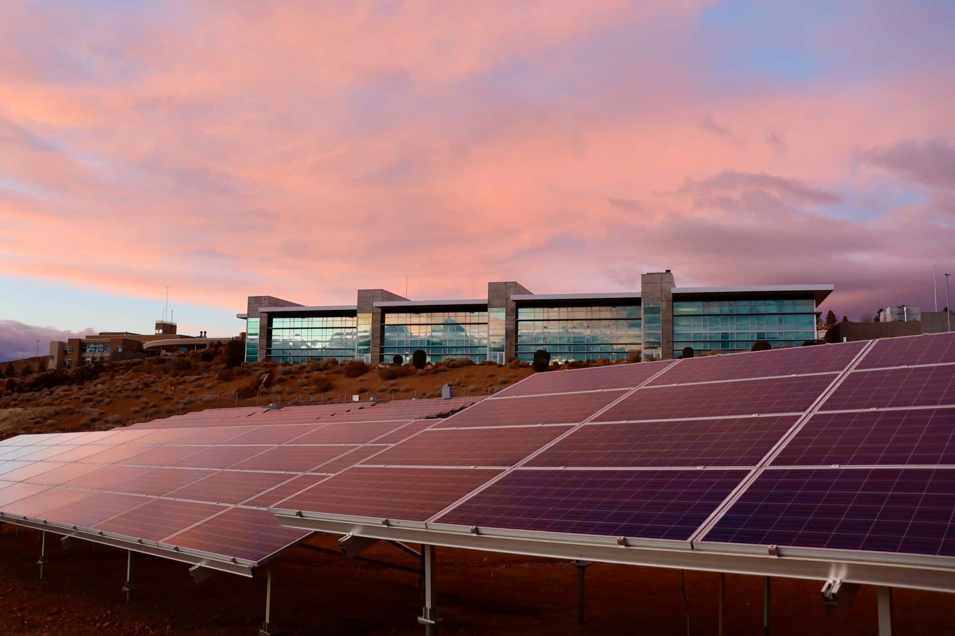 Solar panels mounted on a modern building with a sunset background