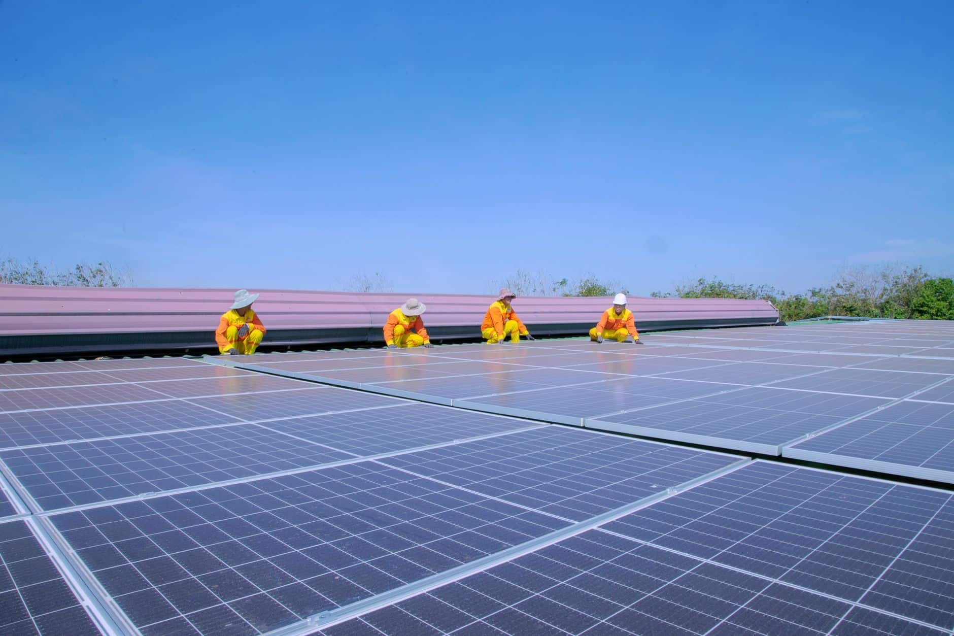 Team of solar technicians installing photovoltaic panels under a clear sky