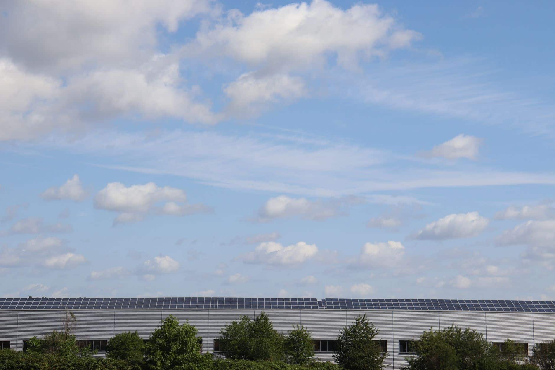 Warehouse roof covered with solar panels under a clear blue sky