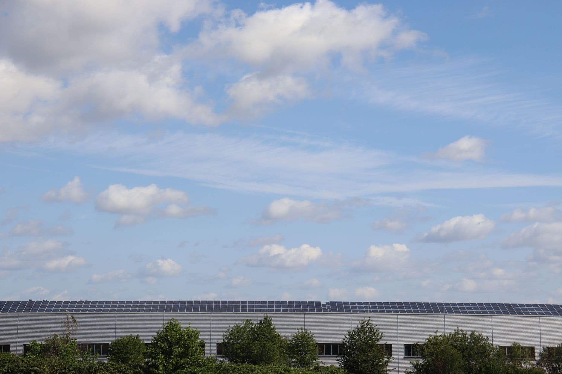 Warehouse roof covered with solar panels under a clear blue sky
