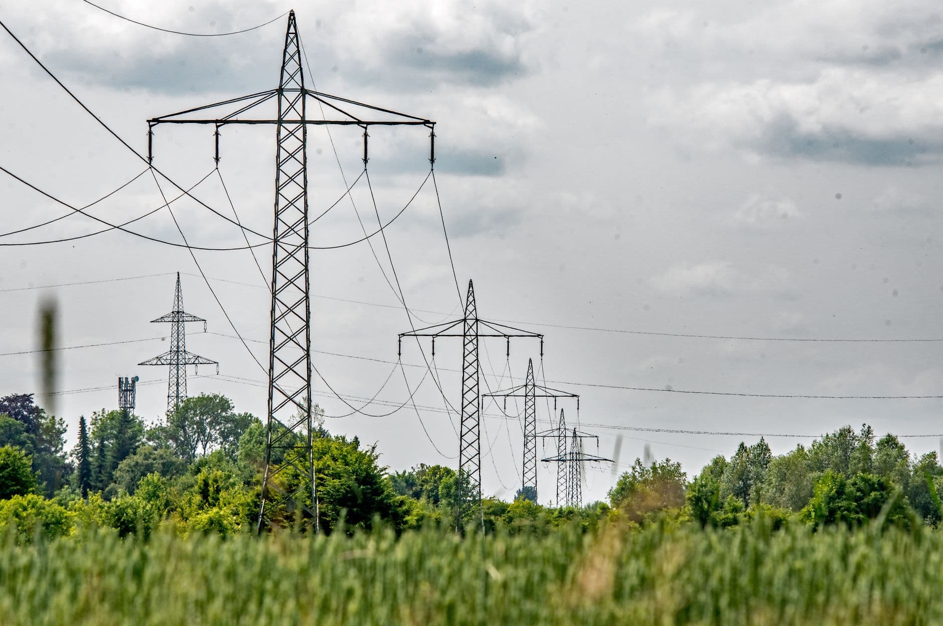 Transmission towers spanning a green field in Bavaria, Germany