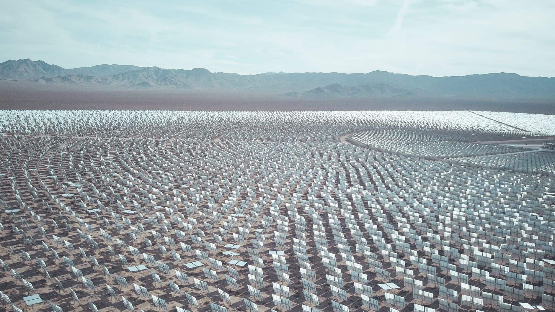 Aerial view of a vast desert solar farm showing rows of photovoltaic panels