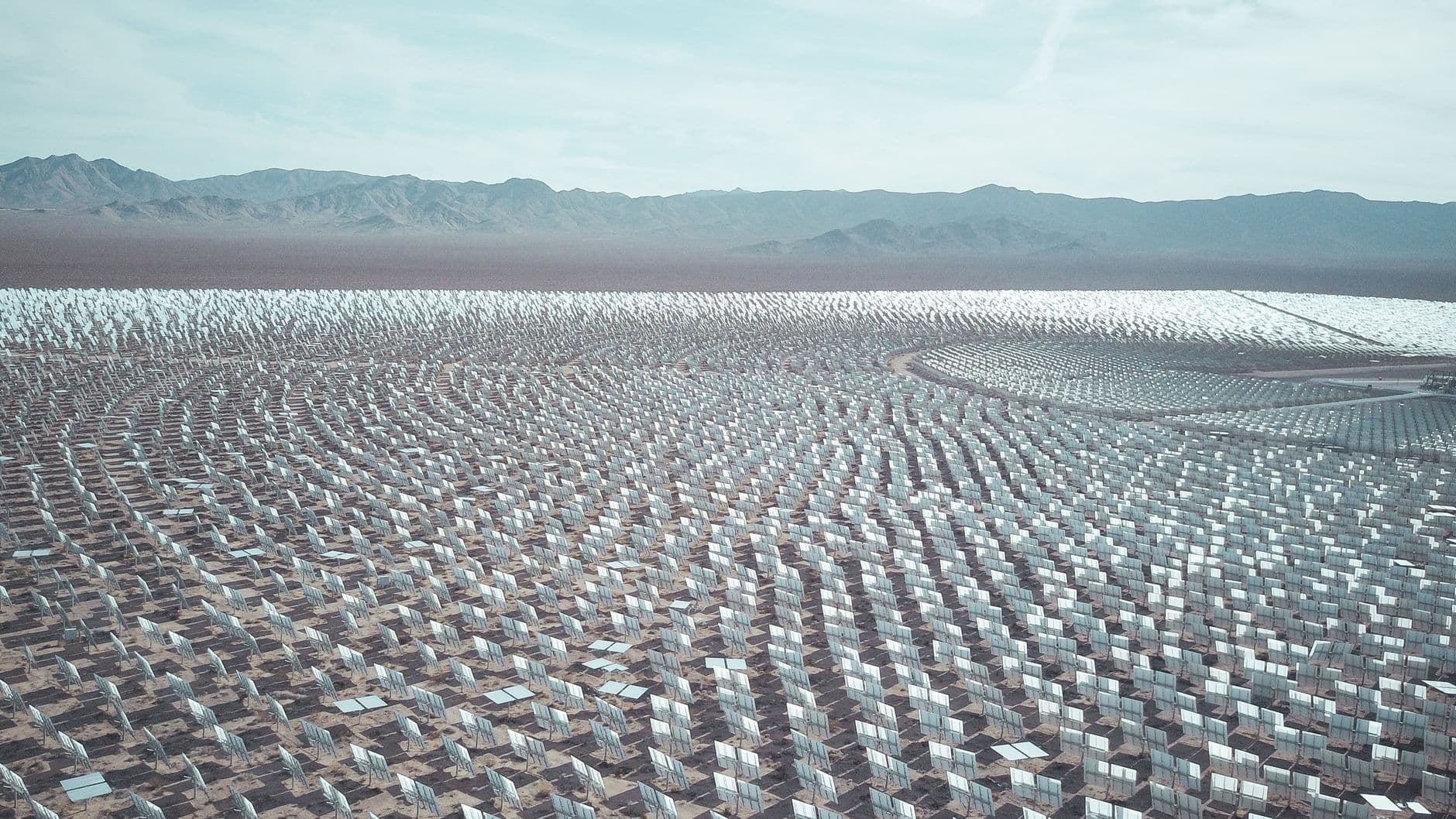 Aerial view of a vast desert solar farm showing rows of photovoltaic panels