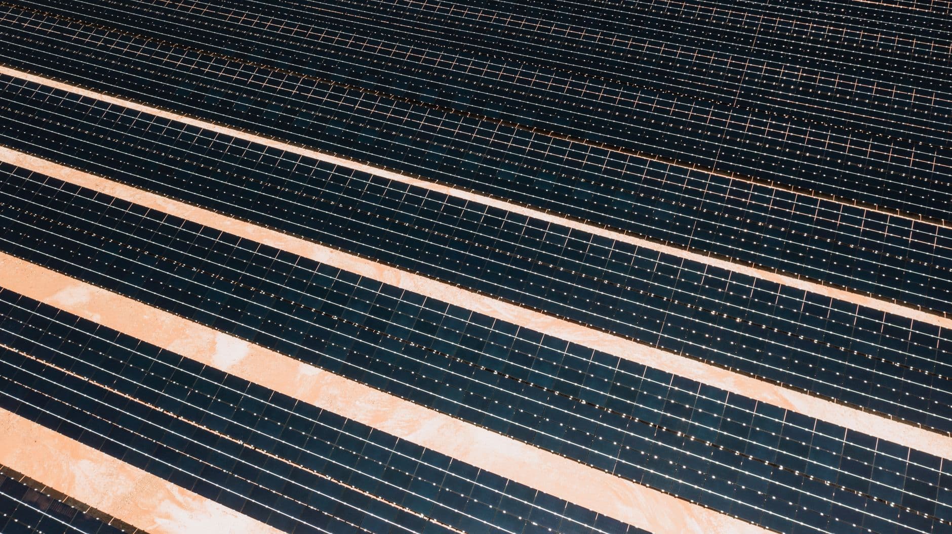 Aerial view of rows of solar panels covering a large area, illustrating renewable energy generation