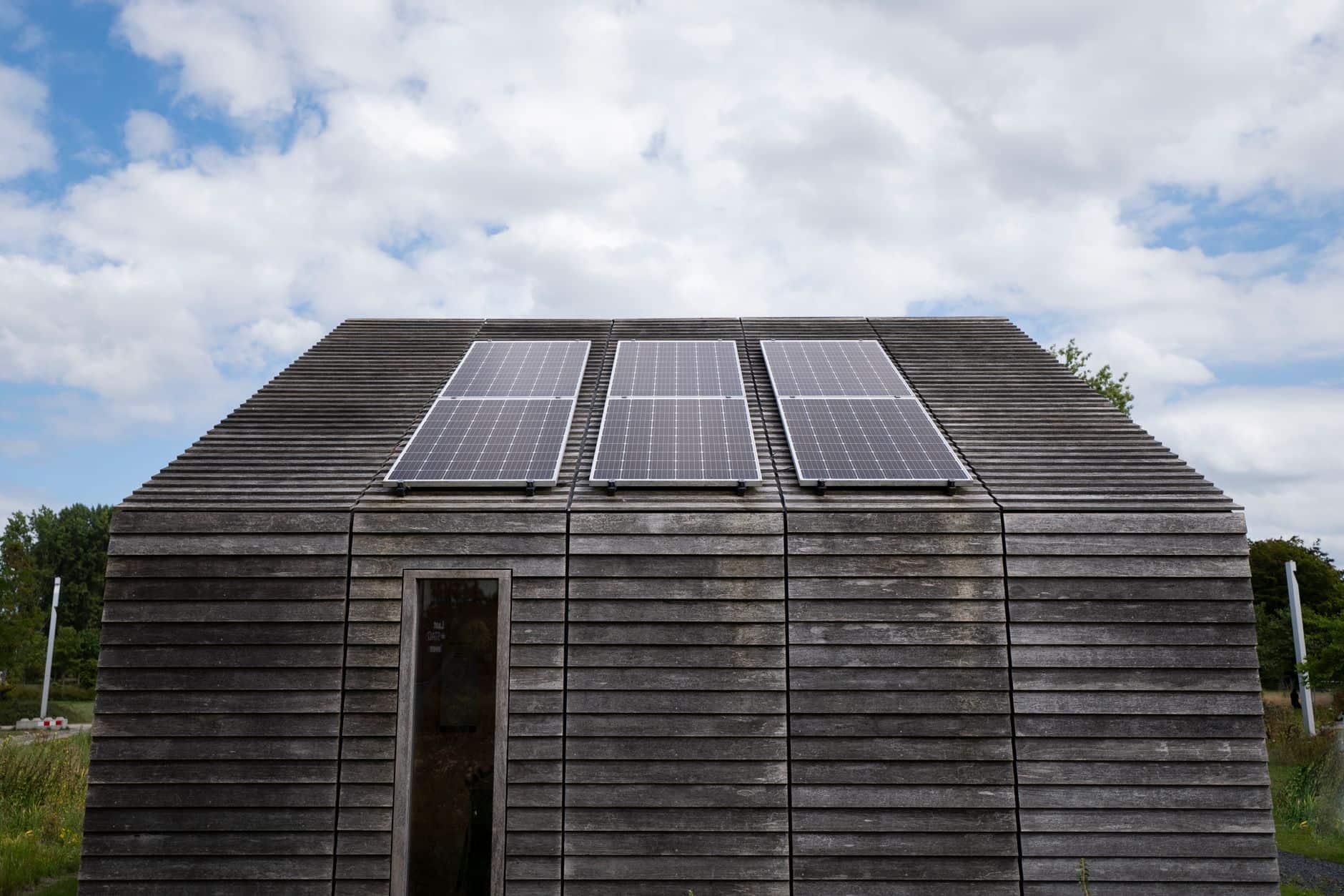 Wooden house with solar panels on the roof under a cloudy sky