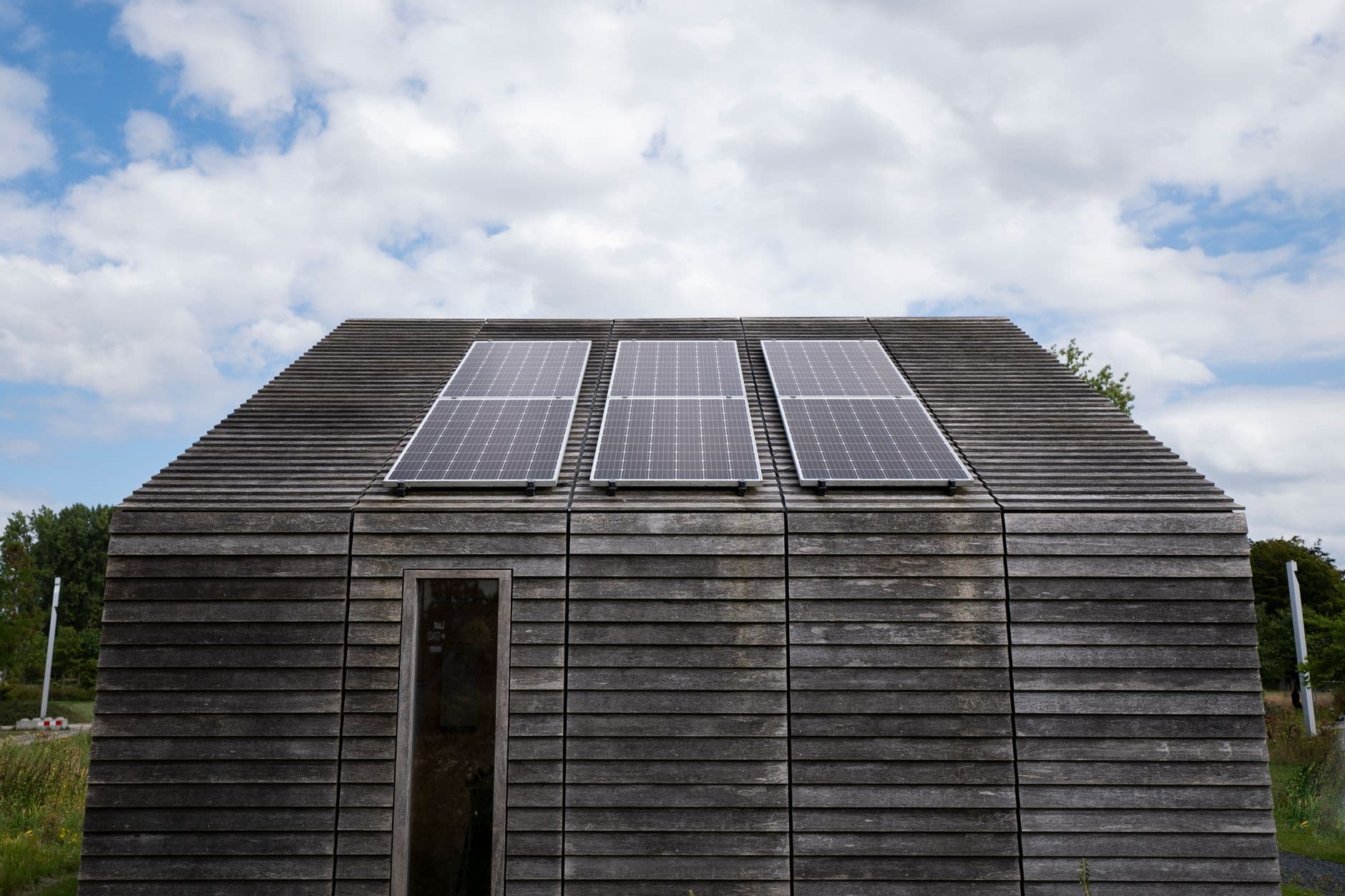 Wooden house with solar panels on the roof under a cloudy sky