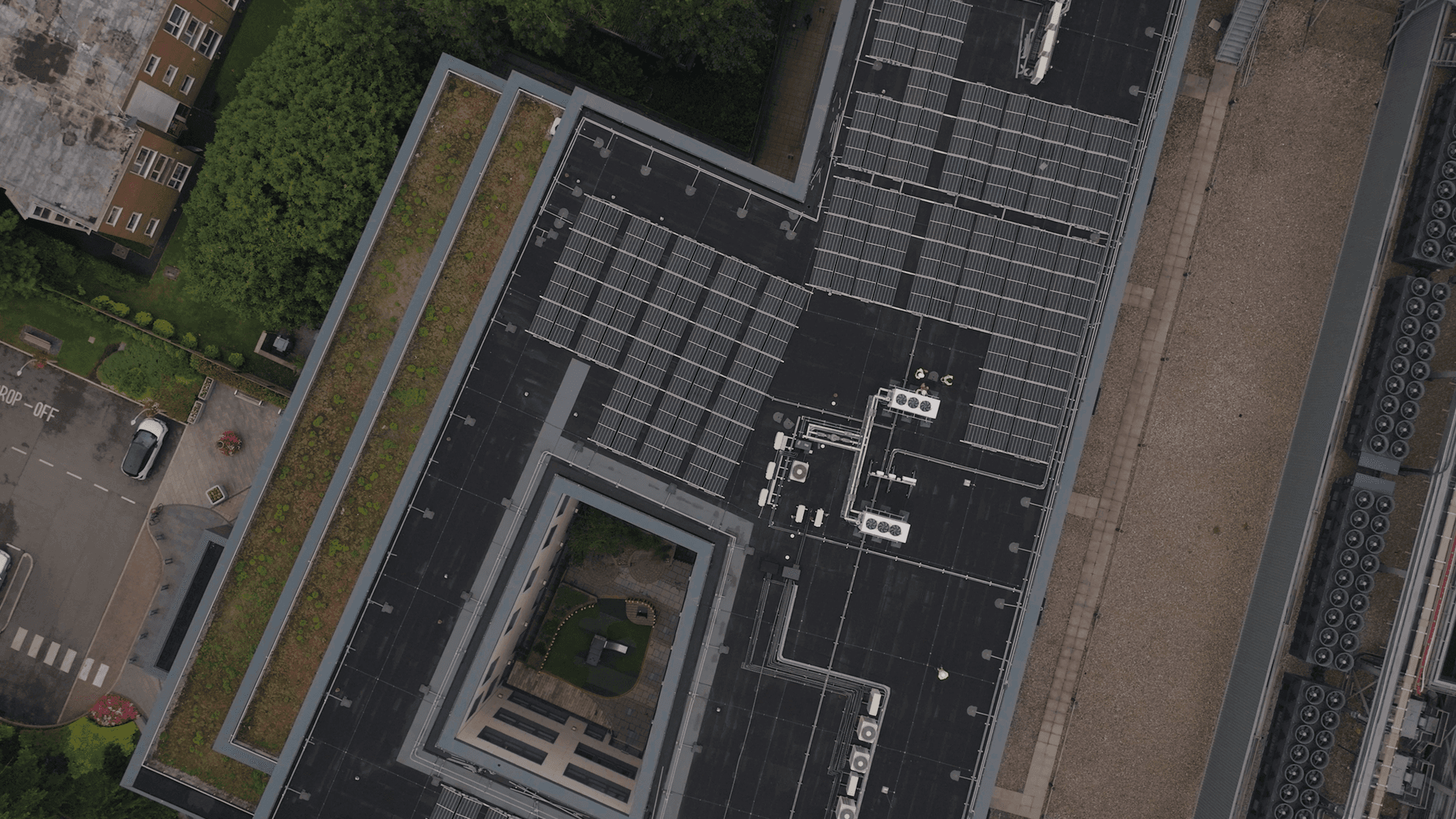 High-angle view of an urban rooftop with solar panels and greenery