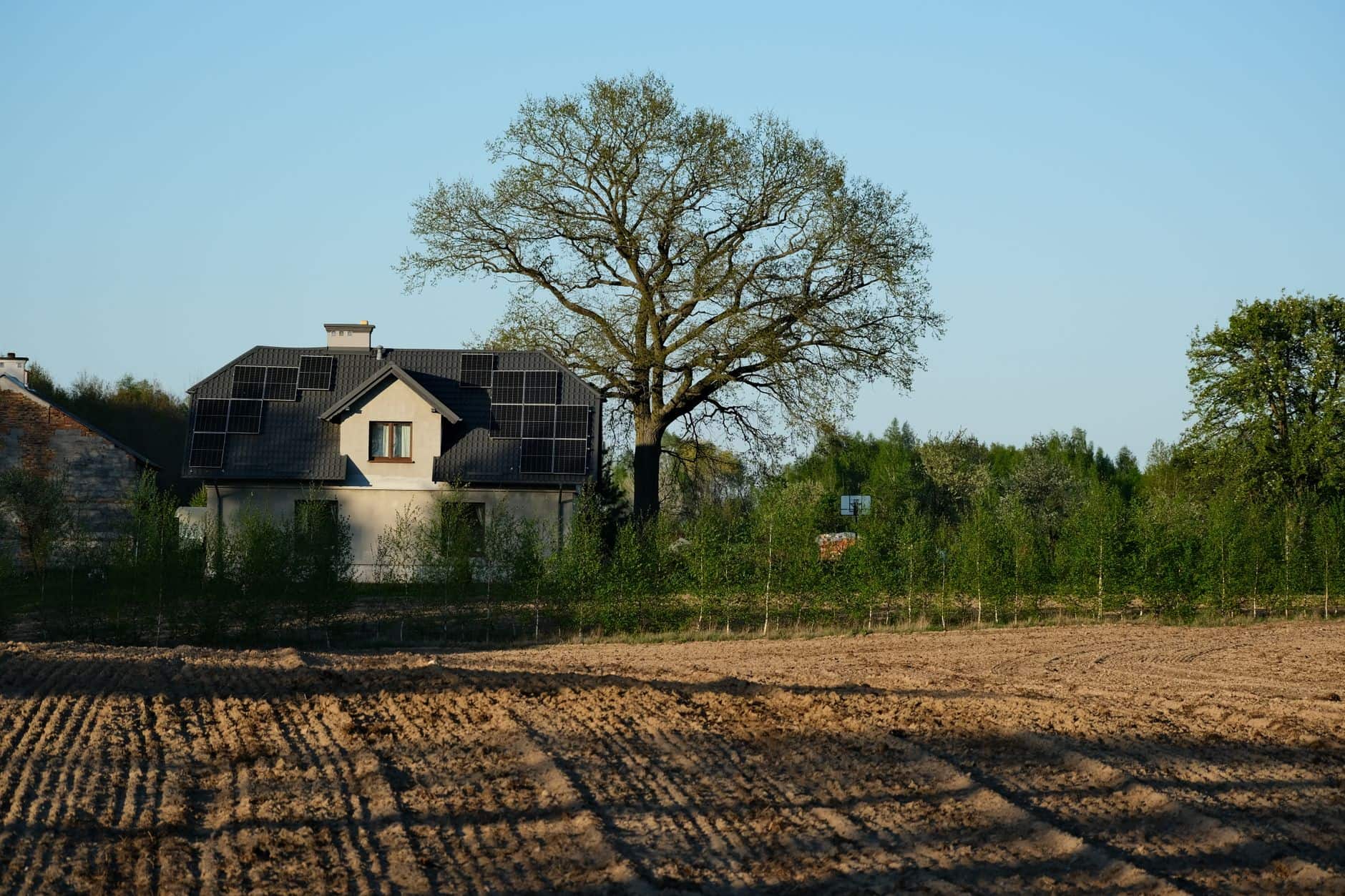 Rural house with rooftop solar panels under a clear blue sky