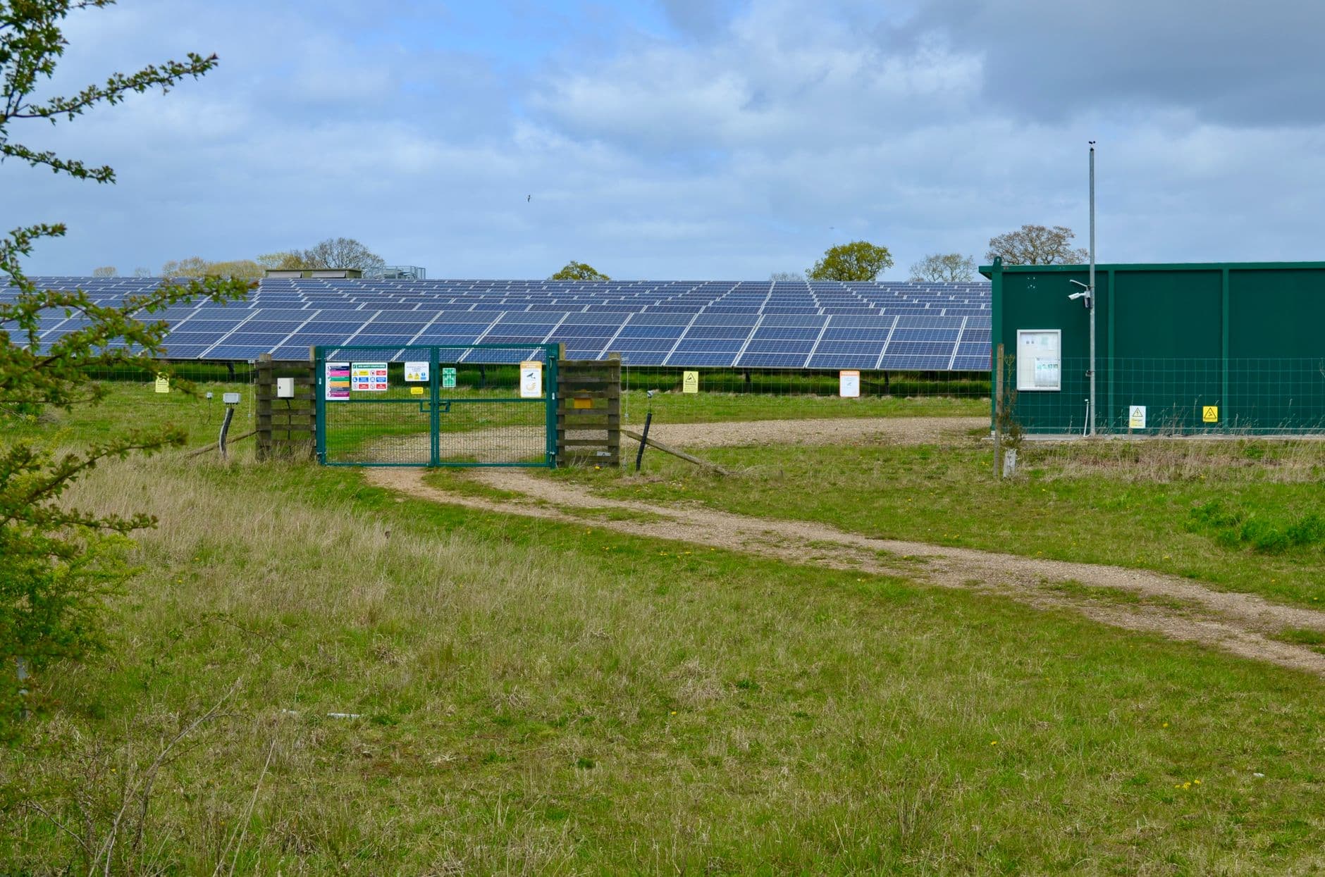 Solar power station with rows of panels in a green field under a cloudy sky