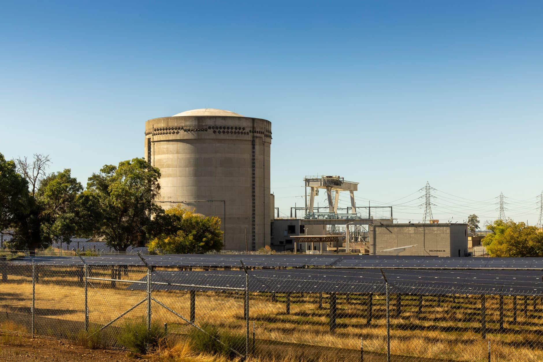 Industrial power plant with cooling tower and solar panels under a clear blue sky