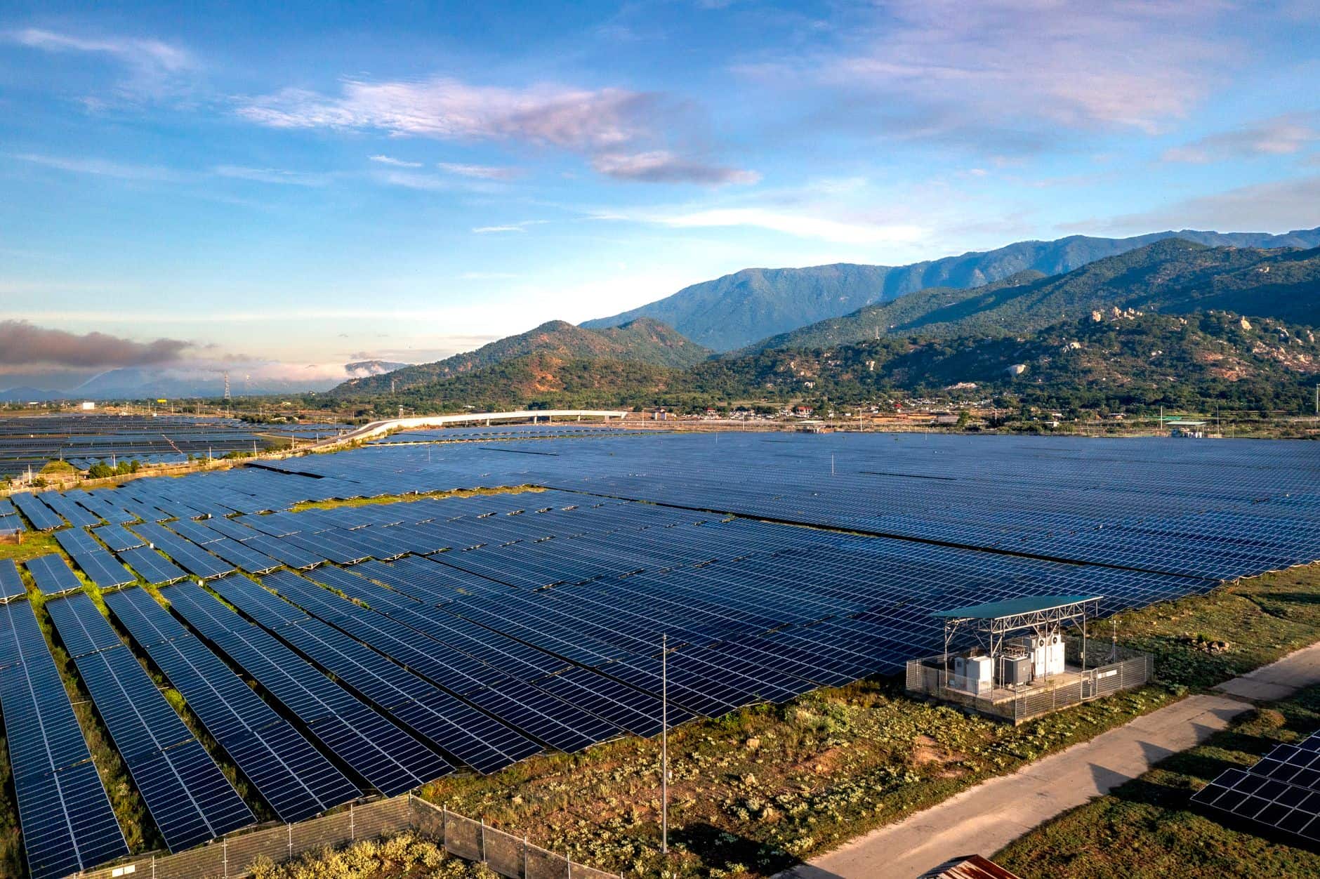 Aerial view of a large solar farm with mountains in the background
