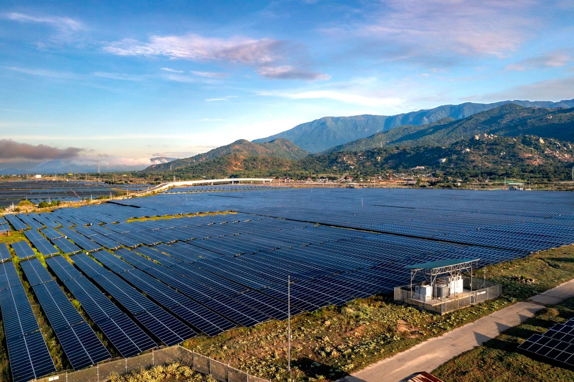 Aerial view of a large solar farm with mountains in the background