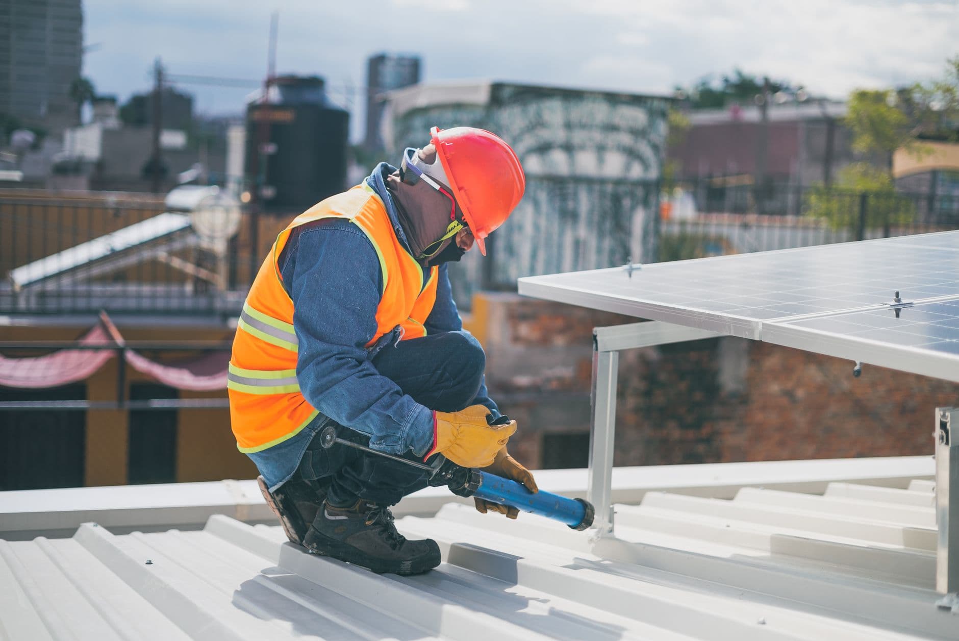 Technician in safety gear installing solar panels on a rooftop