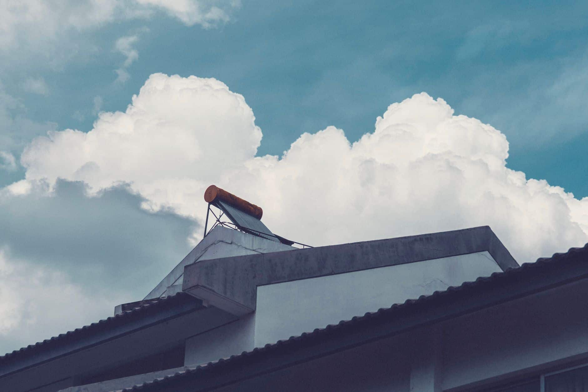 Rooftop with solar water heater against a bright sky