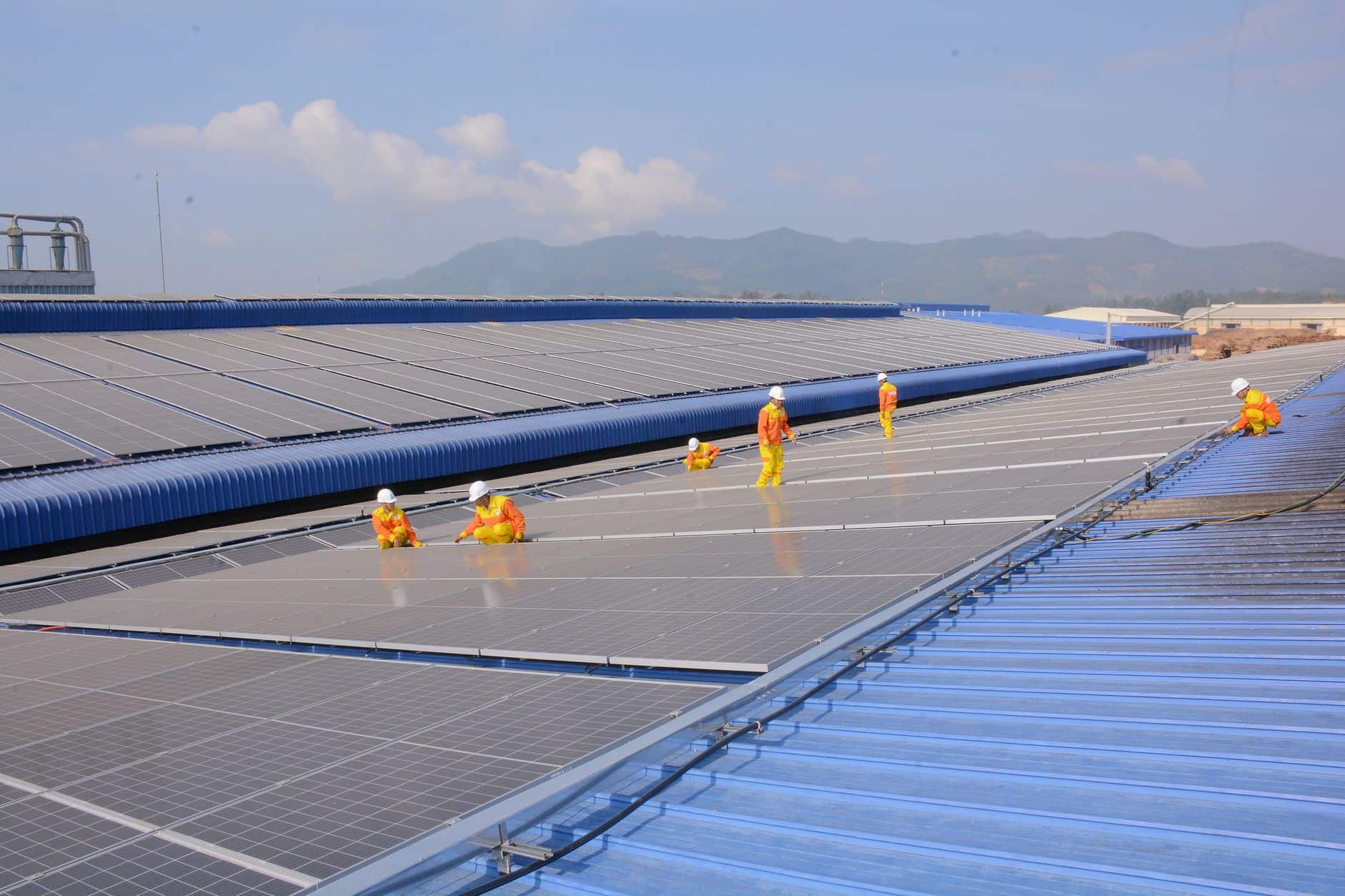 Workers installing solar panels on a large rooftop