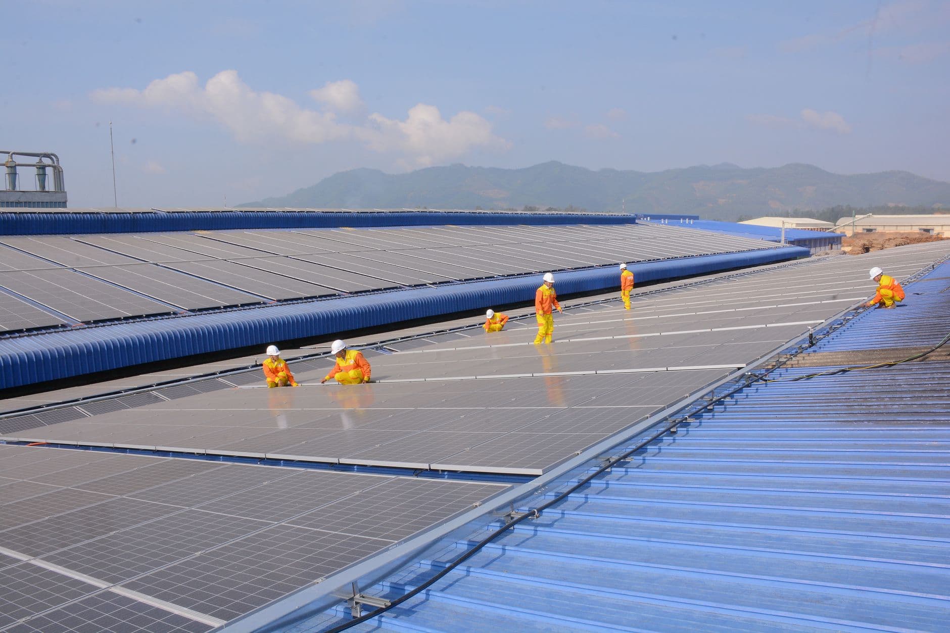 Workers installing solar panels on a large rooftop