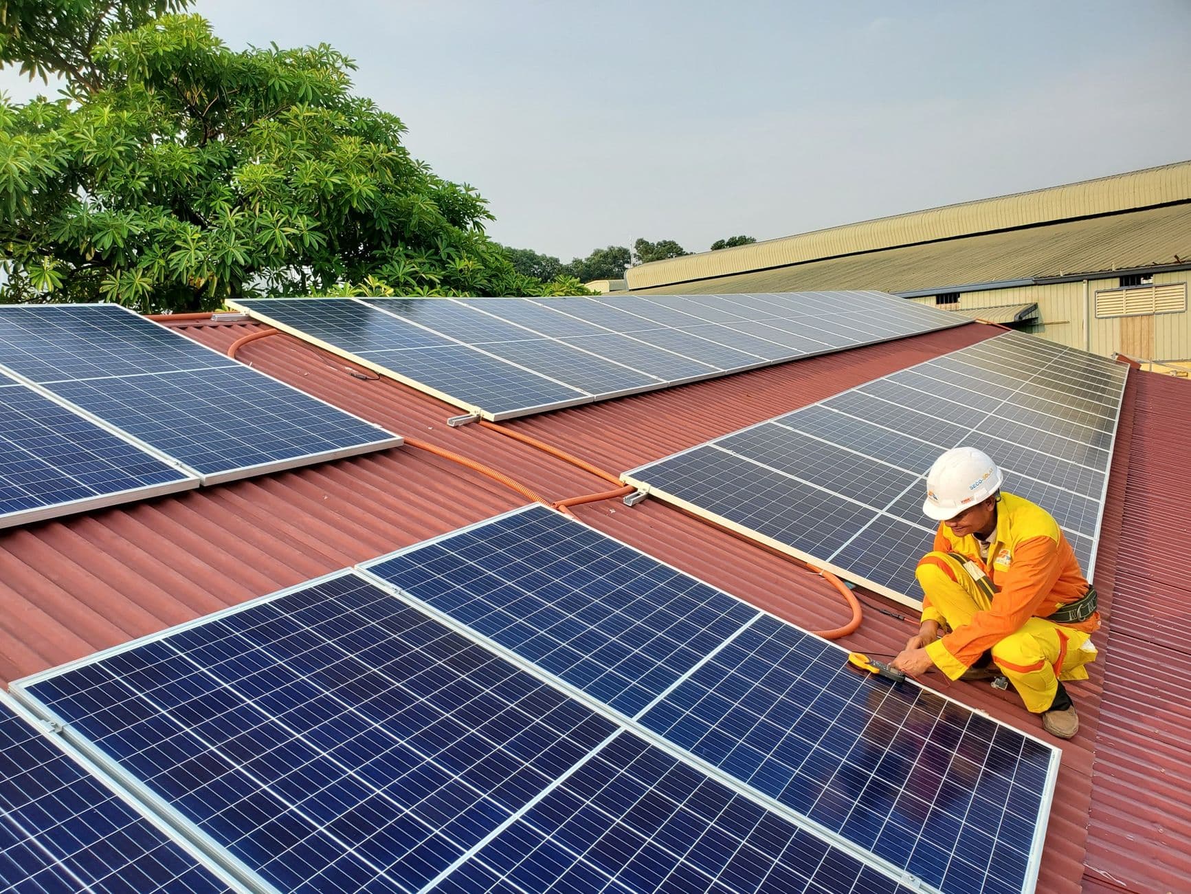 Solar technician performing maintenance on rooftop solar panels